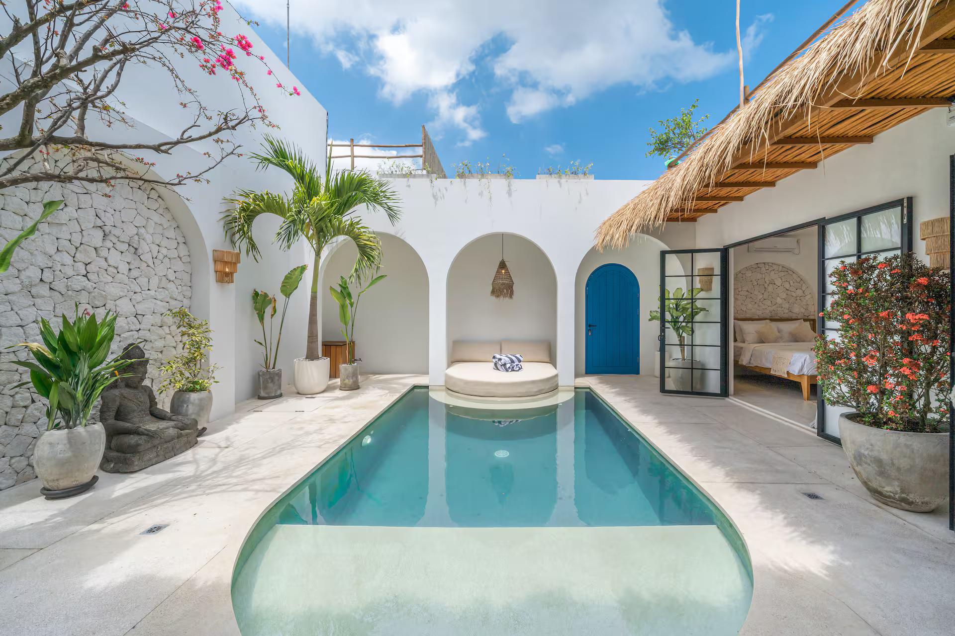The courtyard pool at Villa Dusa, three white arches and a blue timber door at its head