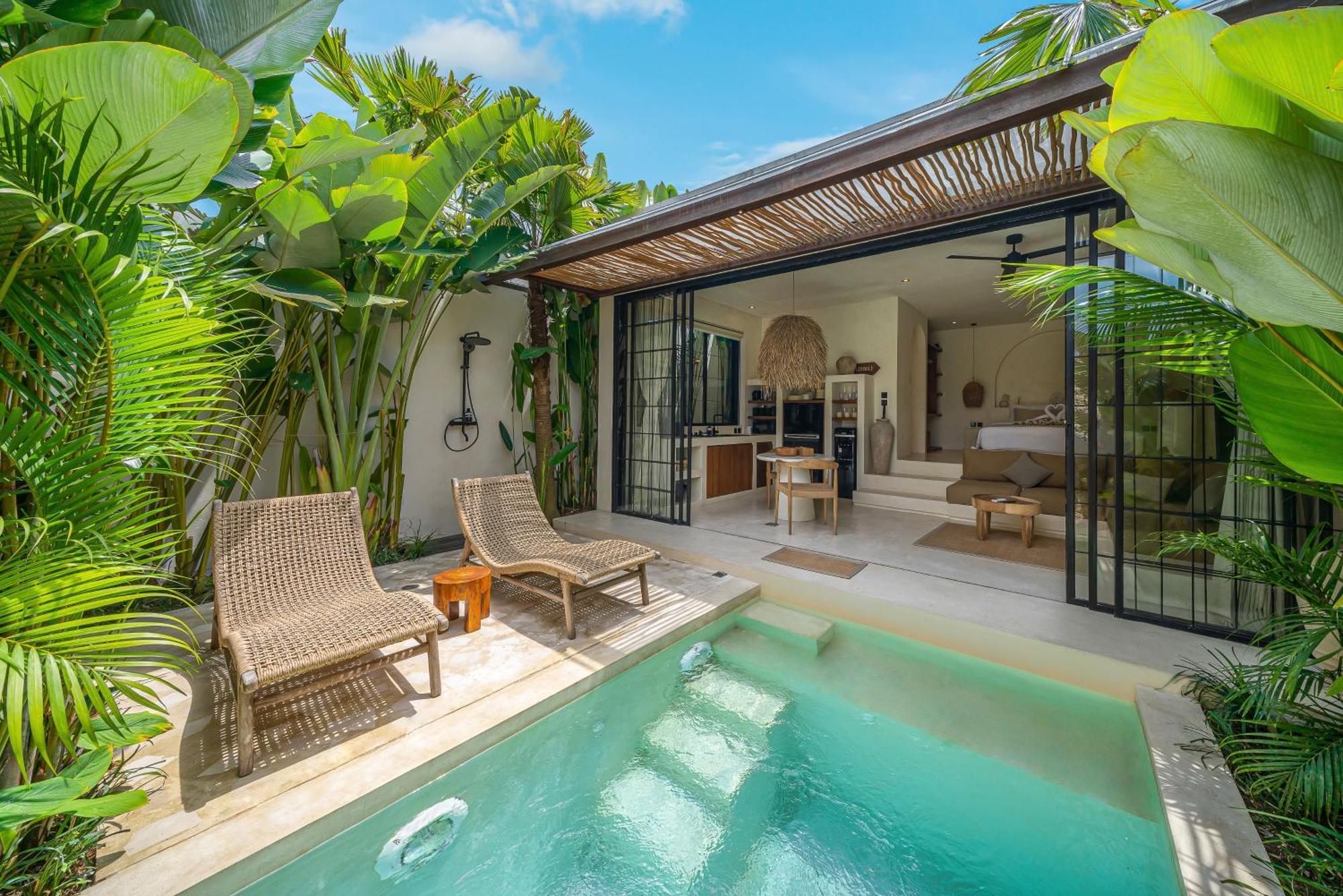The plunge pool at Villa Lumma 3, with woven loungers under a reed pergola and the glass pavilion beyond