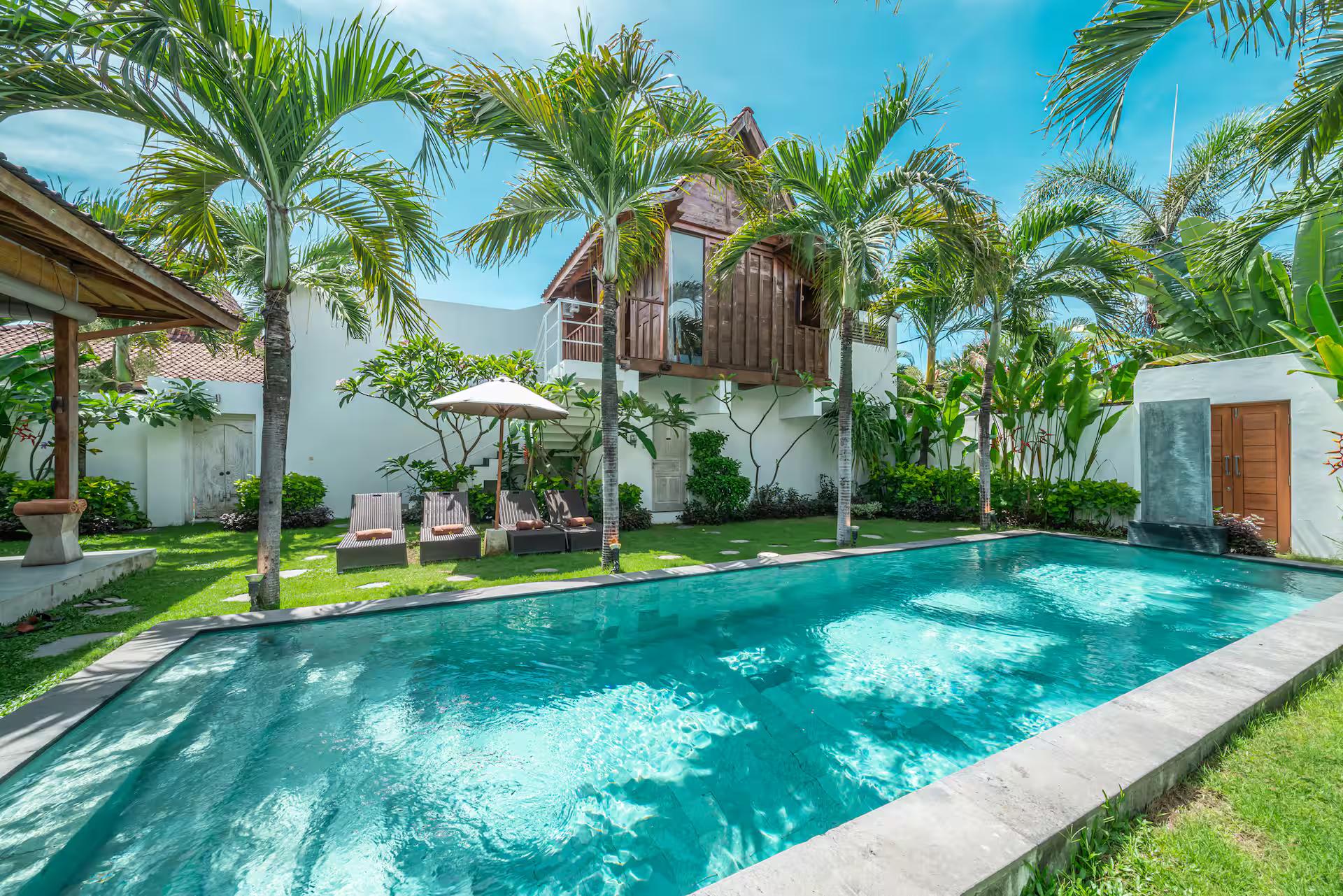 The palm-lined pool at Villa Palm Tree, with the timber loft house rising behind