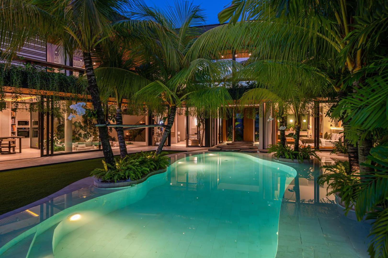 The lagoon-shaped pool at Villa Coco Bay curving through palms below the timber house