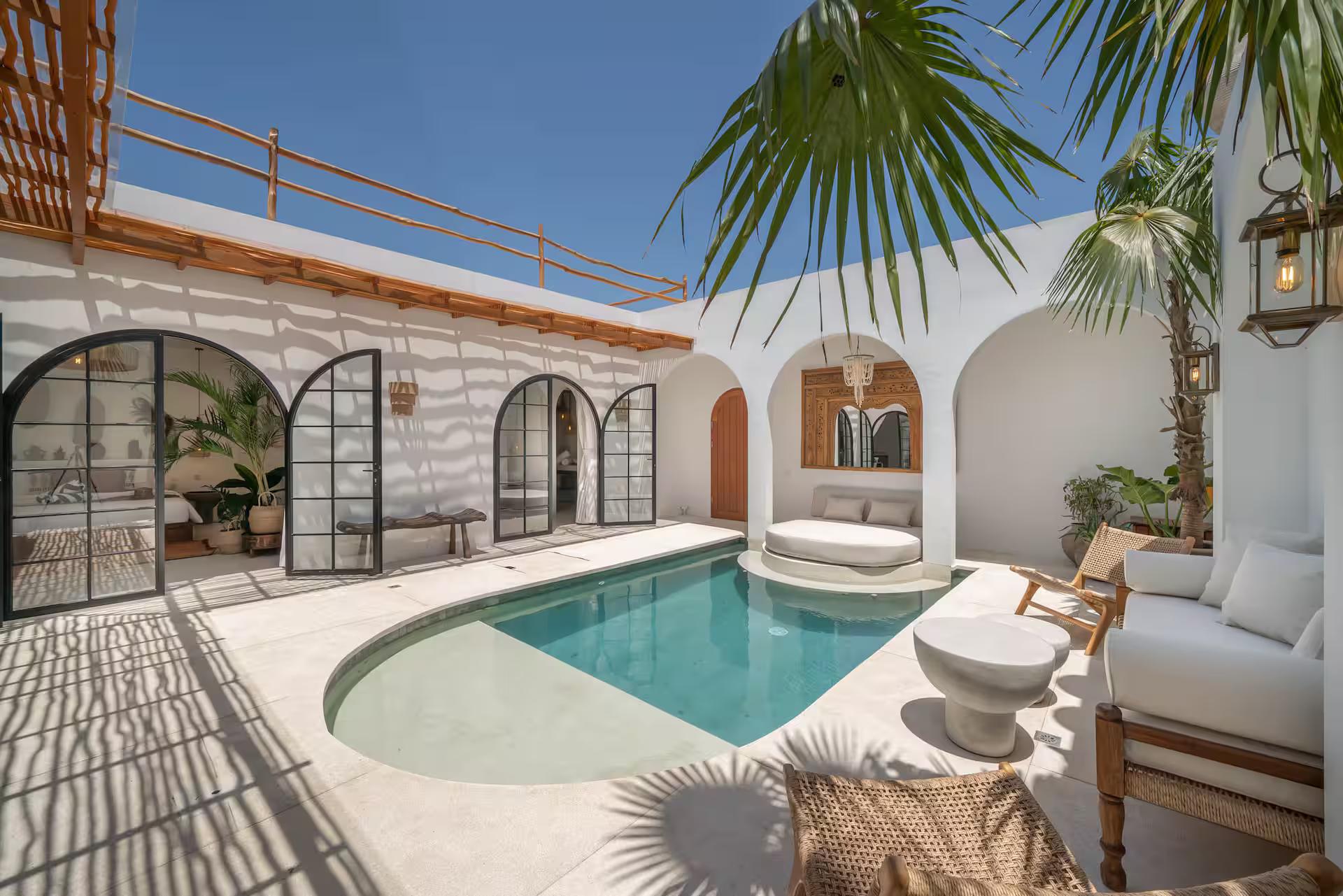 The curved pool at Villa Heiwa in its courtyard of white arches, fan palms overhead