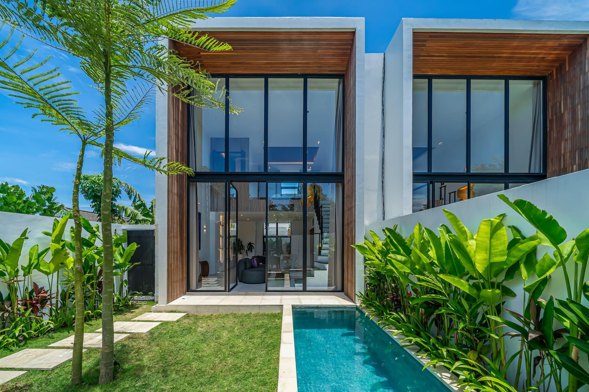 Aether Villa's lap pool and lawn running the length of the walled garden to the two-storey glass facade