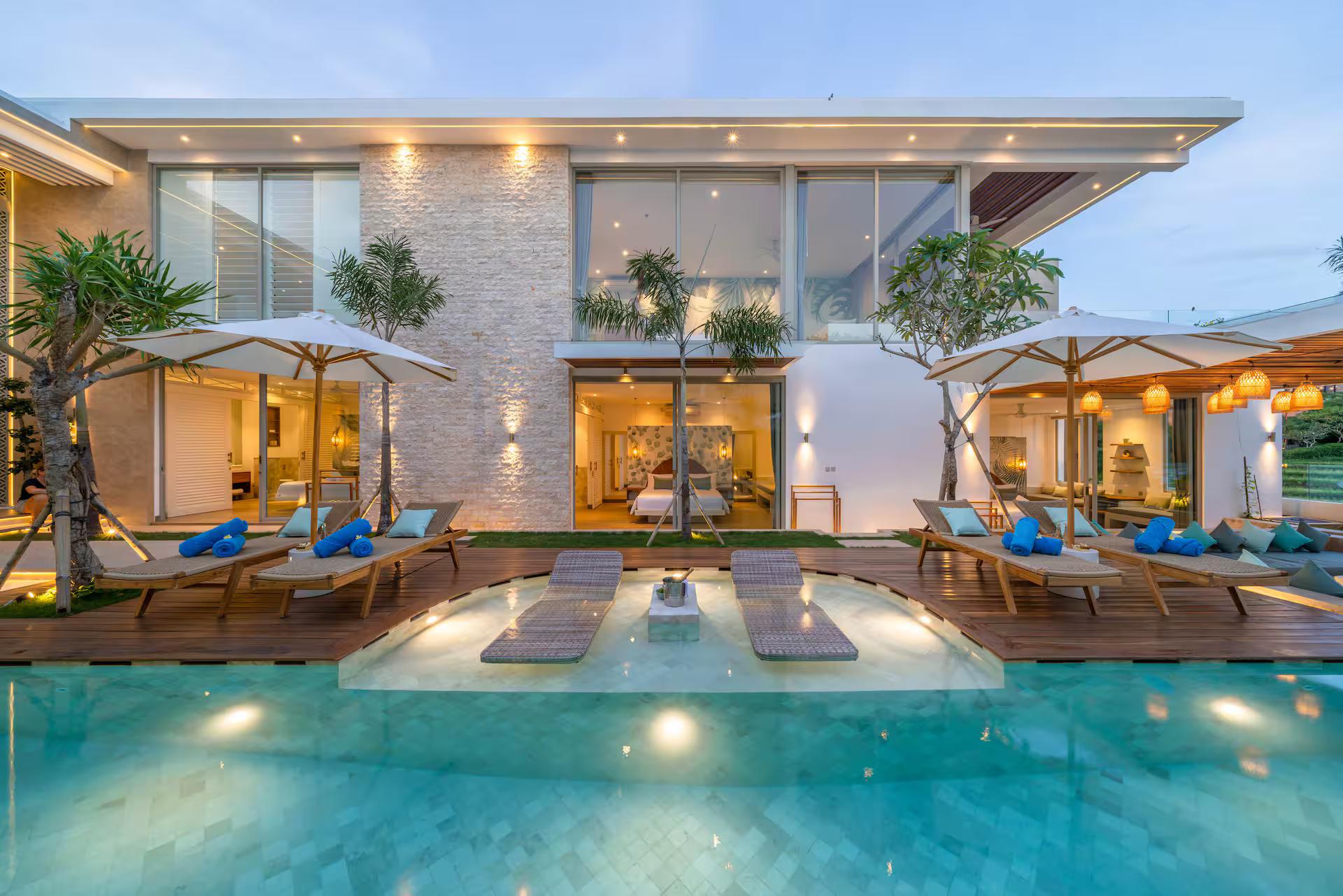 Villa Vida & Vola from across the pool, glass walls and parasols along the terrace