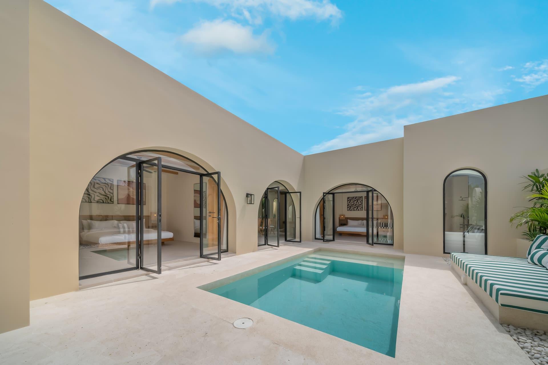 Villa Sorrento's walled courtyard: a rectangular pool between white arches, striped daybeds alongside