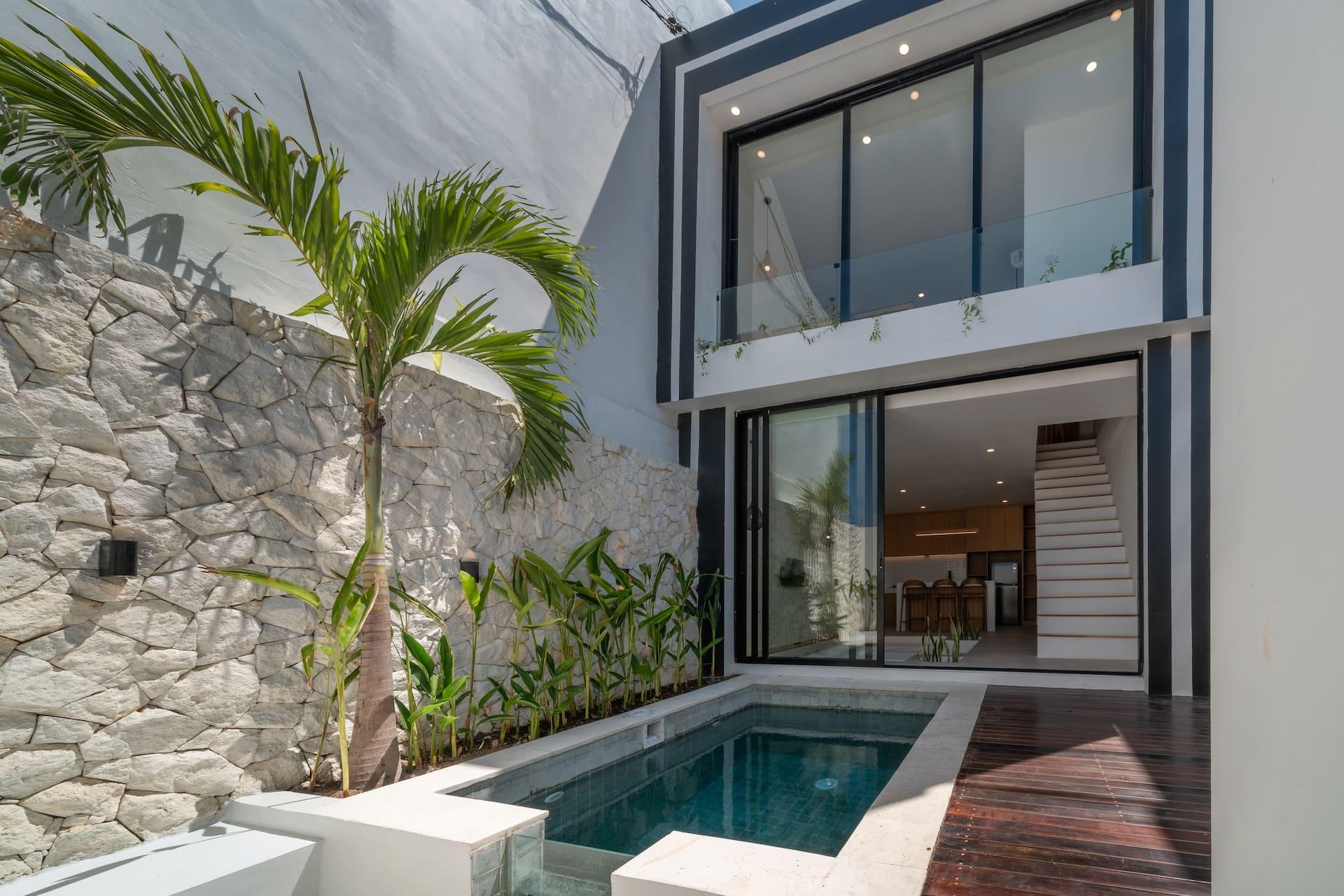 Villa Merine's two-storey white facade rising above its green-tiled plunge pool and palm-planted stone wall