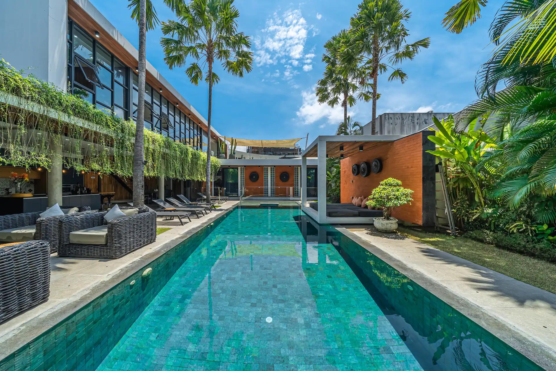 The lap pool at Villa Aless running the depth of the garden between palms and glass