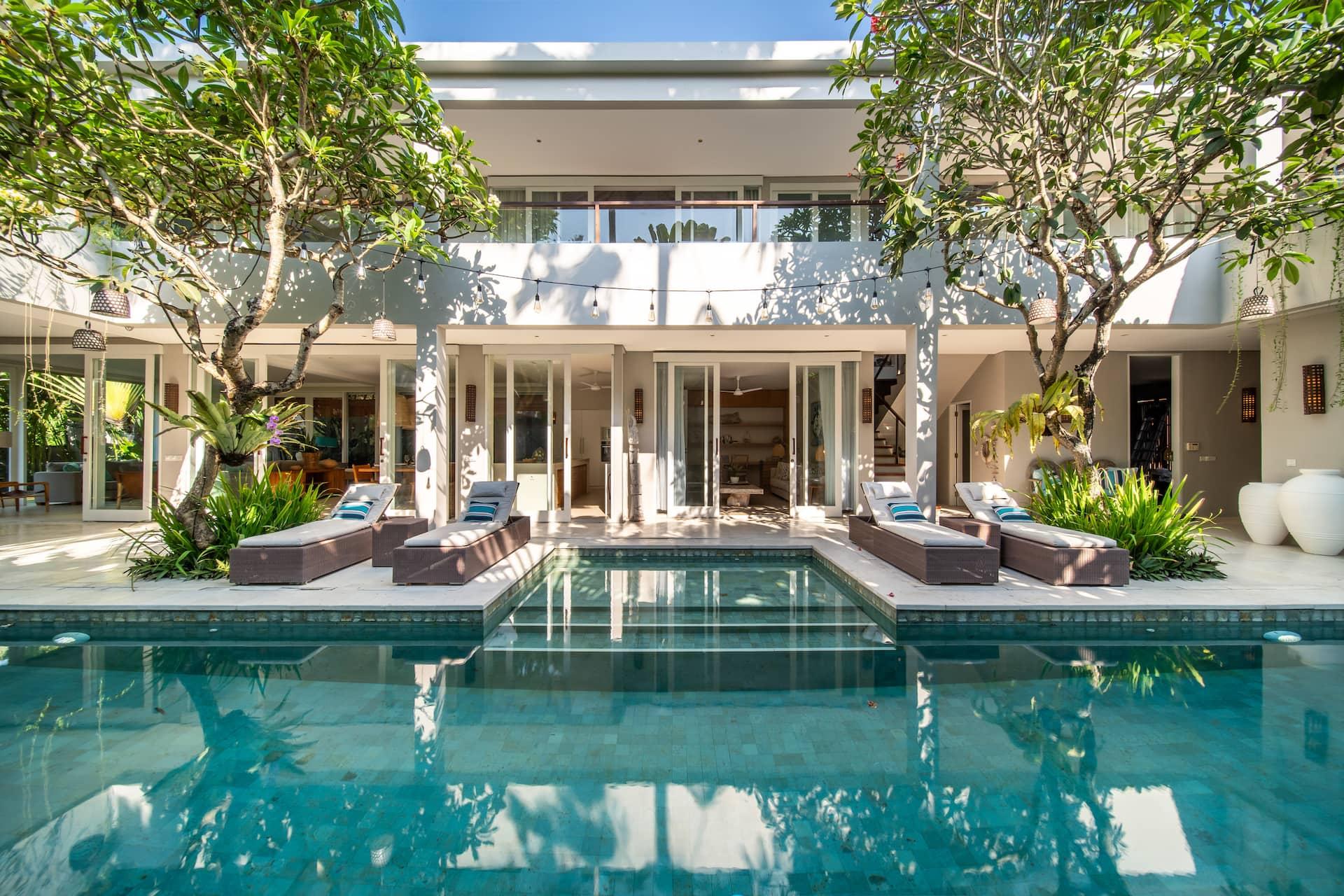 Villa Sunsara 2's 15-metre pool with sun loungers, frangipani trees and the two-storey white villa behind