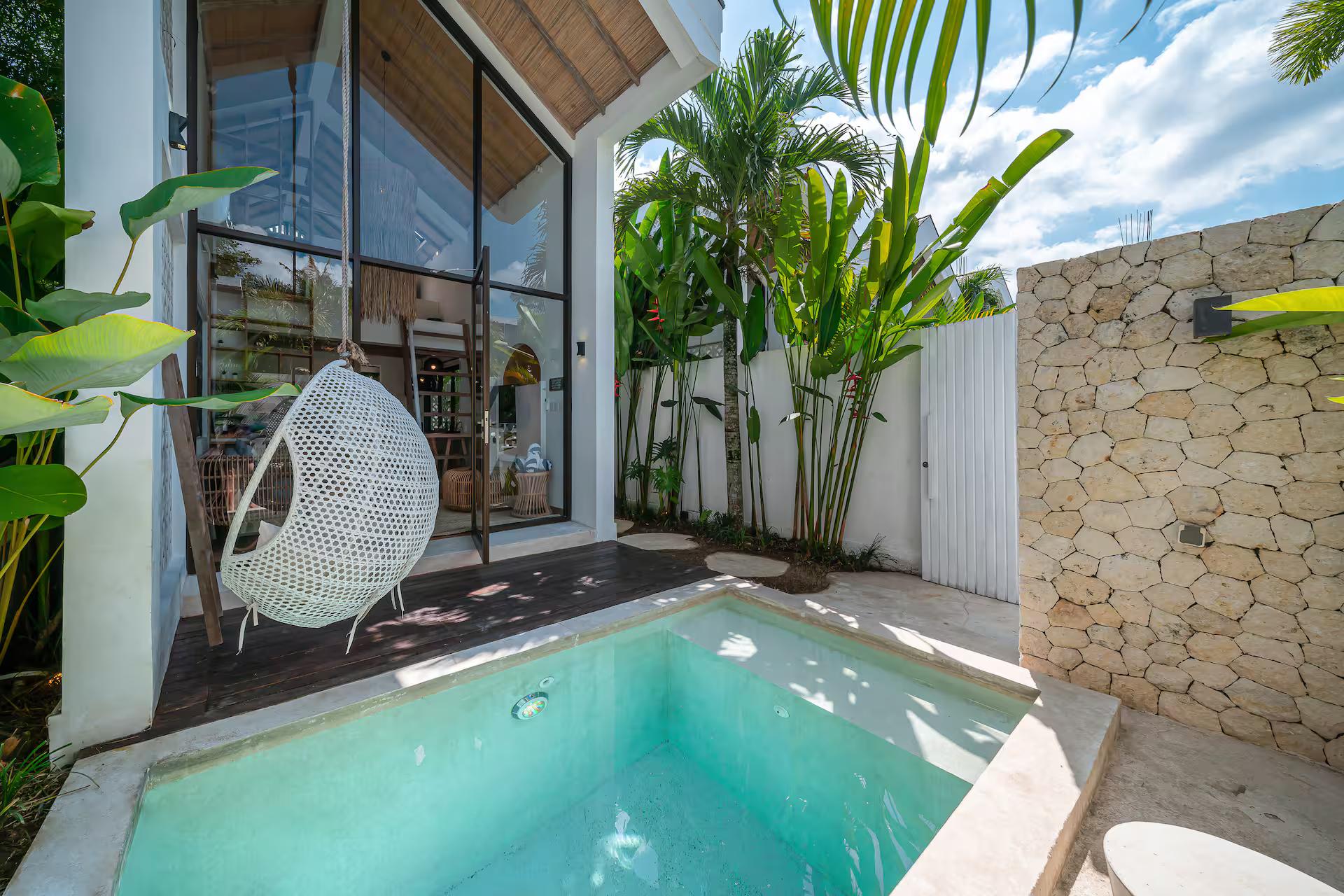 The plunge pool at Villa Tiny 2, hanging rattan egg chair beside the glazed A-frame gable