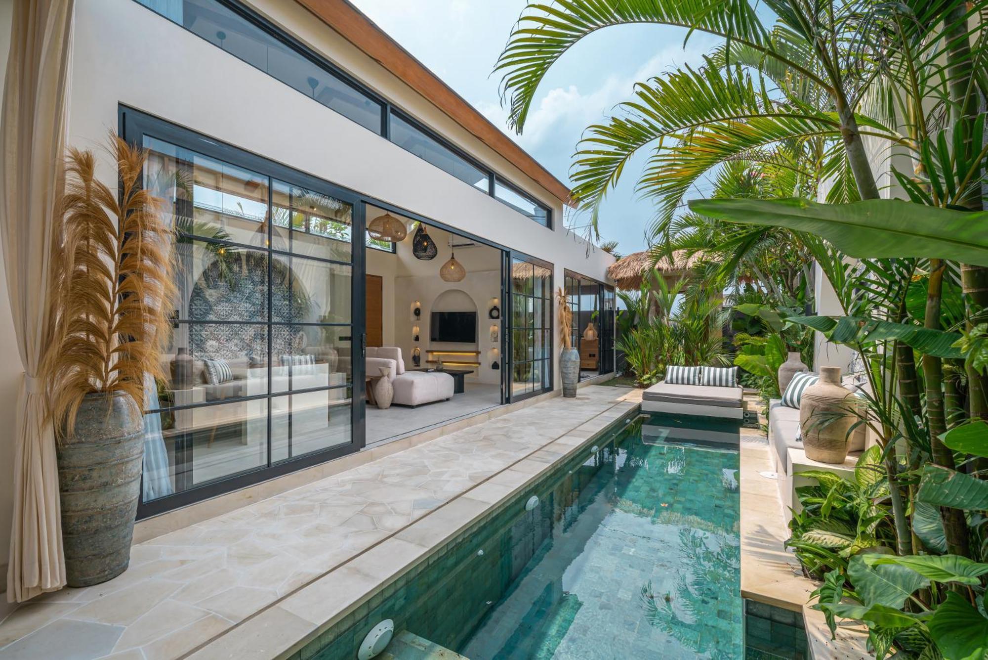 The green-tiled pool at Villa Isly running between the glass facade and the stone wall