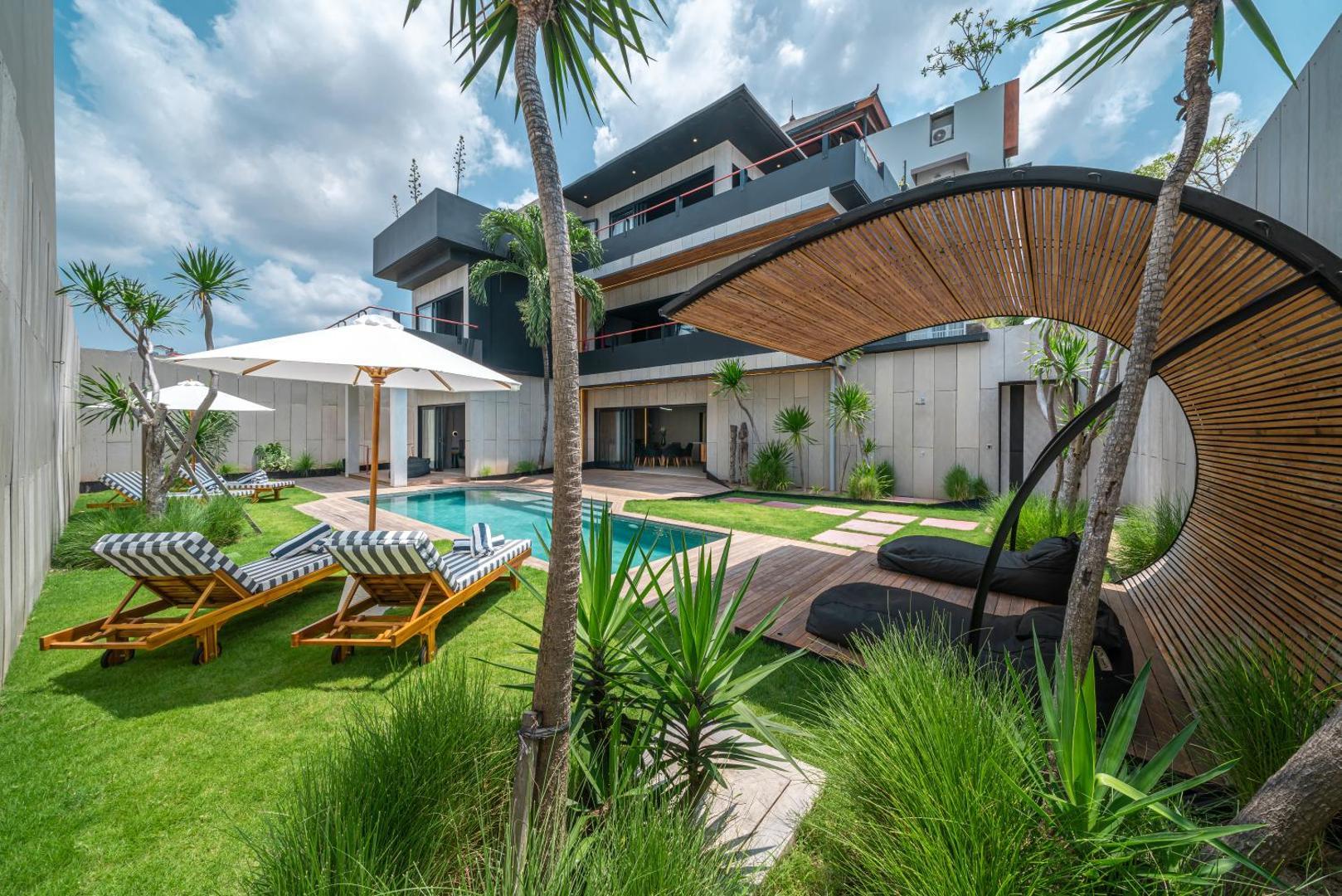 A coiled bamboo sculpture standing on the lawn beside the pool and loungers