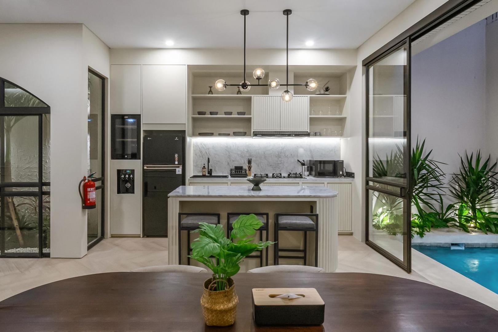 Oval dining table and kitchen island looking through to the pool courtyard