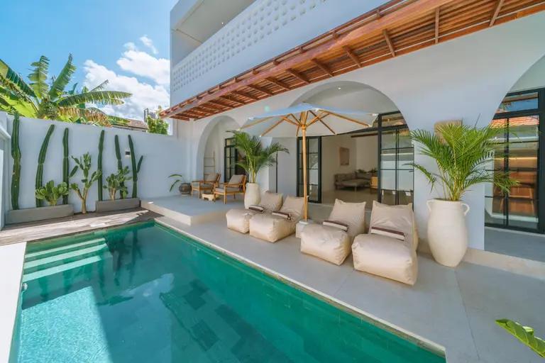 Beanbags beside the pool at Villa Eliad, a wall of columnar cactus rising behind
