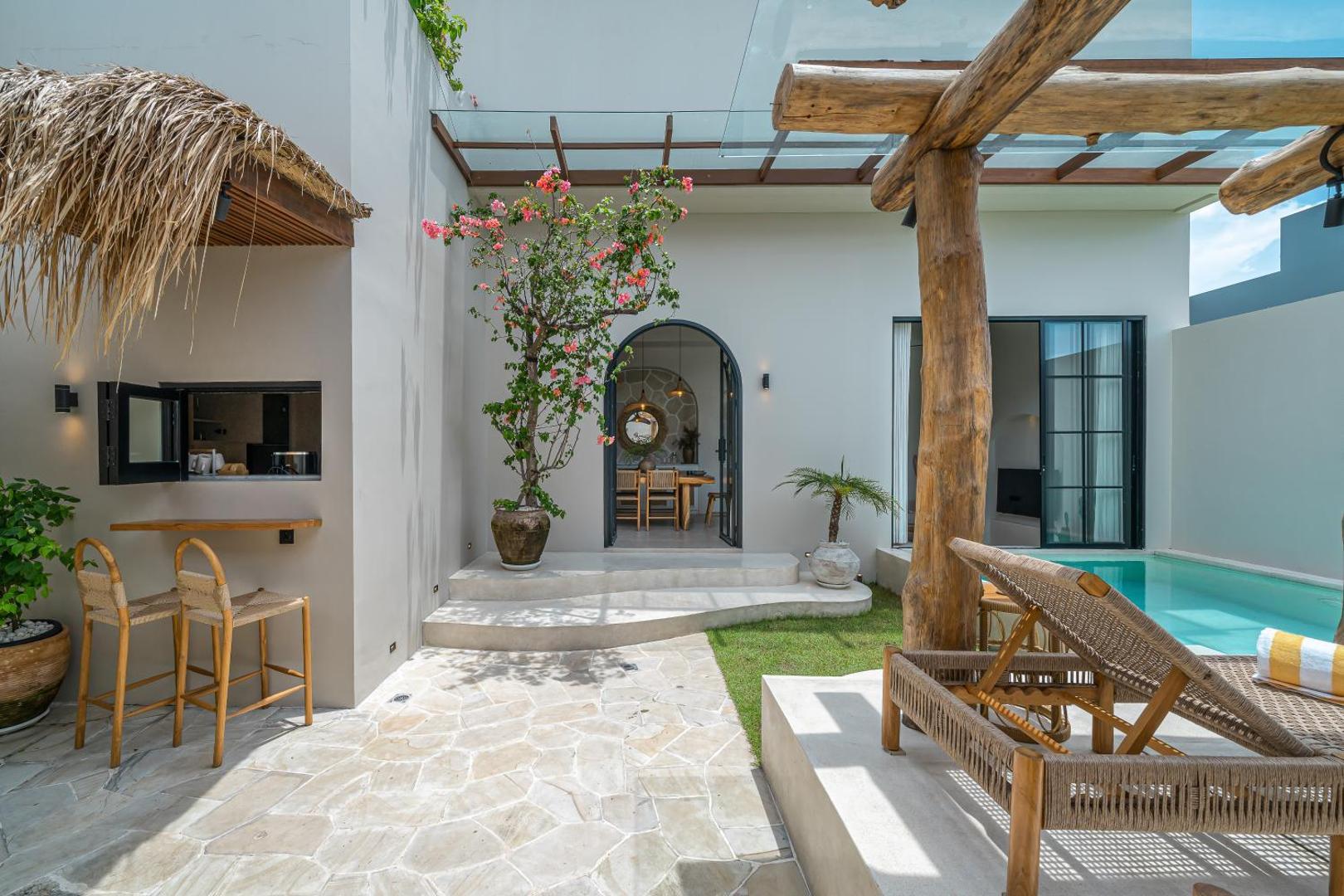 The outdoor bar corner under its thatched awning, bougainvillea climbing the pergola beyond