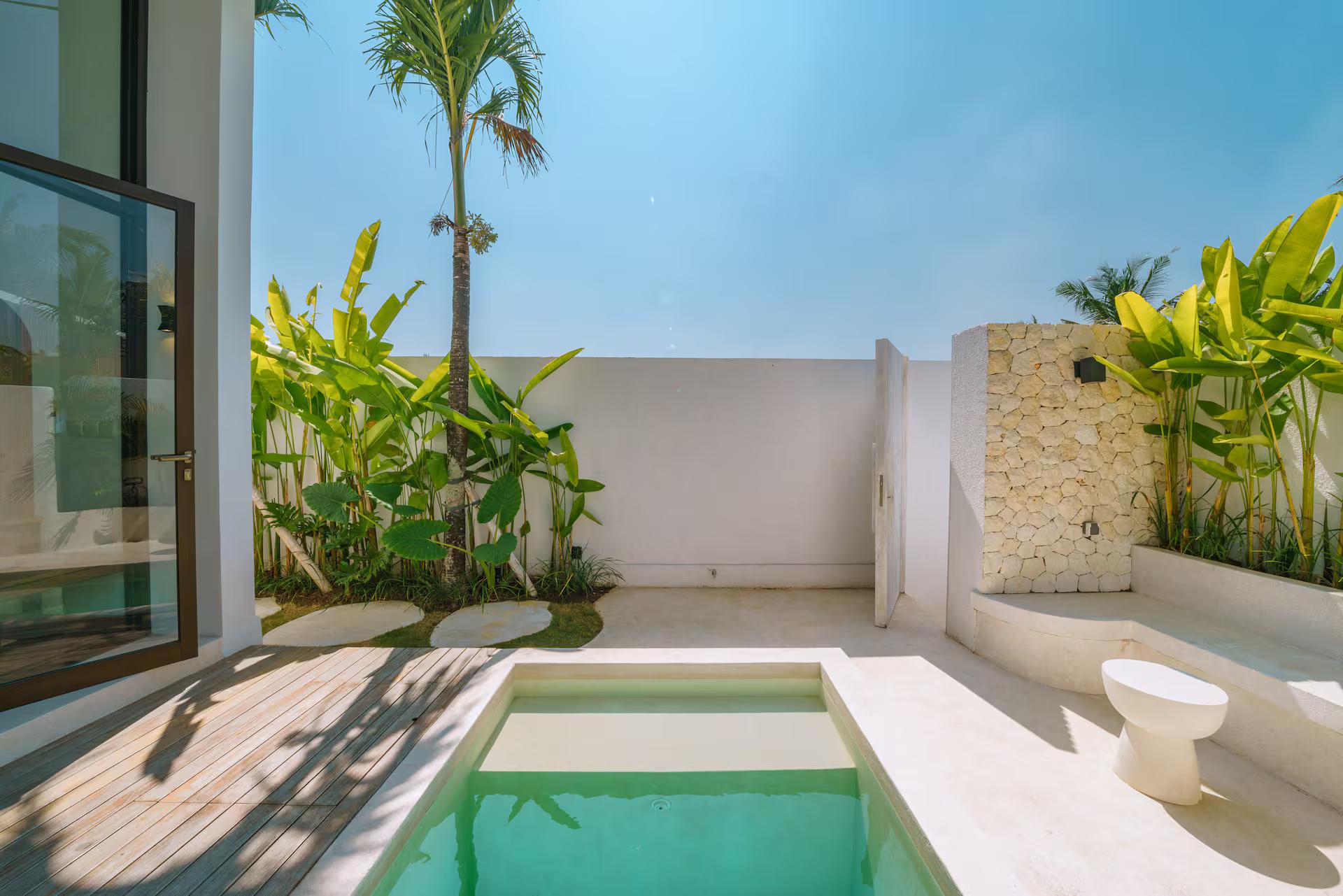 White bathing ledge and stone stools at the pool edge, coral-stone wall behind