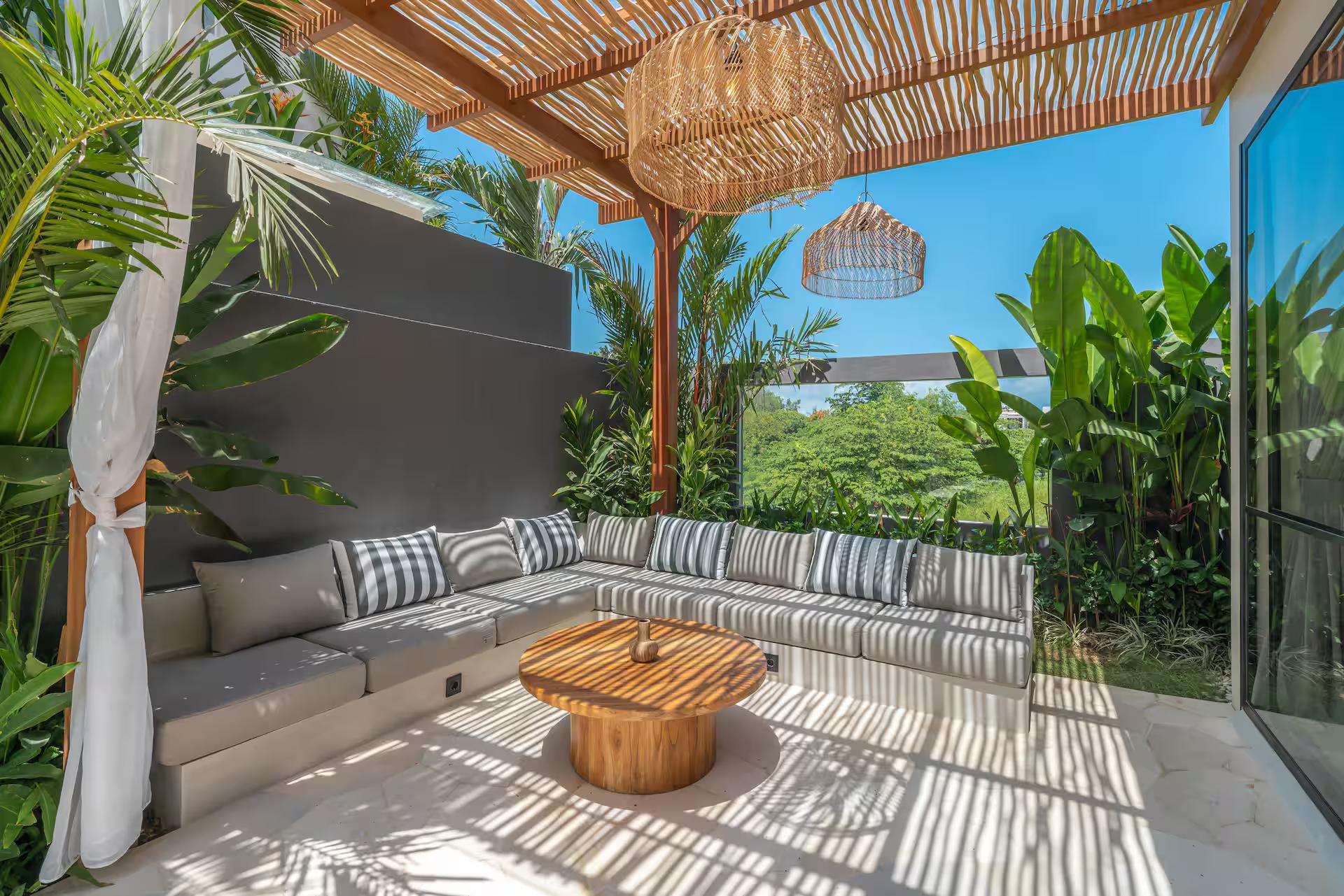 Built-in bench of striped cushions under the bamboo-and-thatch bale beside the pool