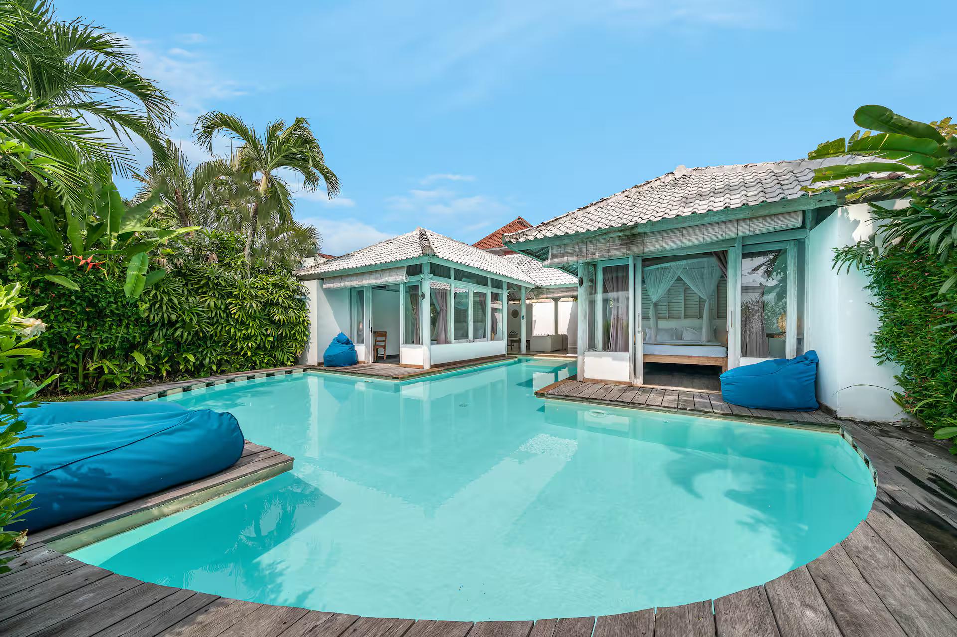 Rounded end of the pool with blue bean bags on the curved timber deck and lawn behind