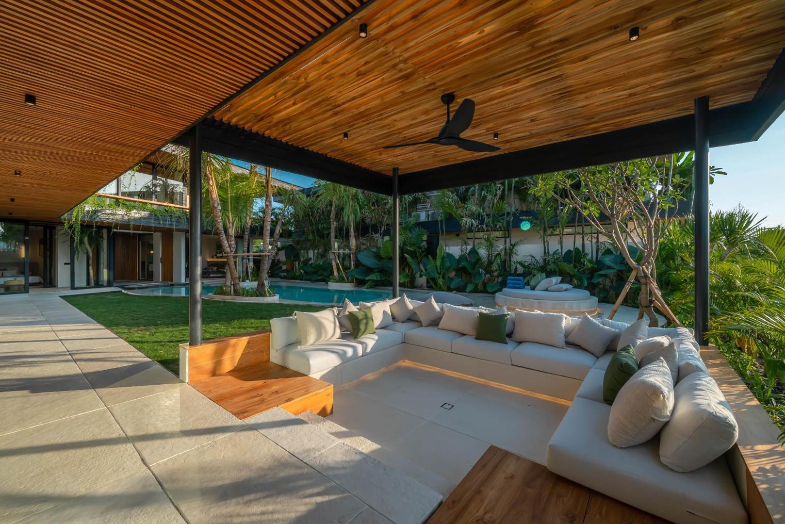 Deep sofas in the garden pavilion under a slatted timber canopy beside the lawn
