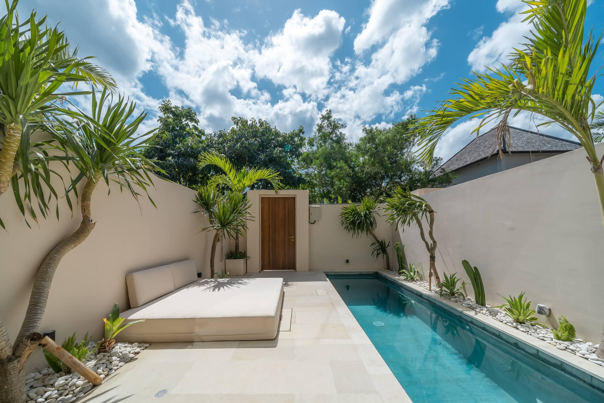 A white sun platform sits beside the pool at Enso 4, framed by pandanus and palms