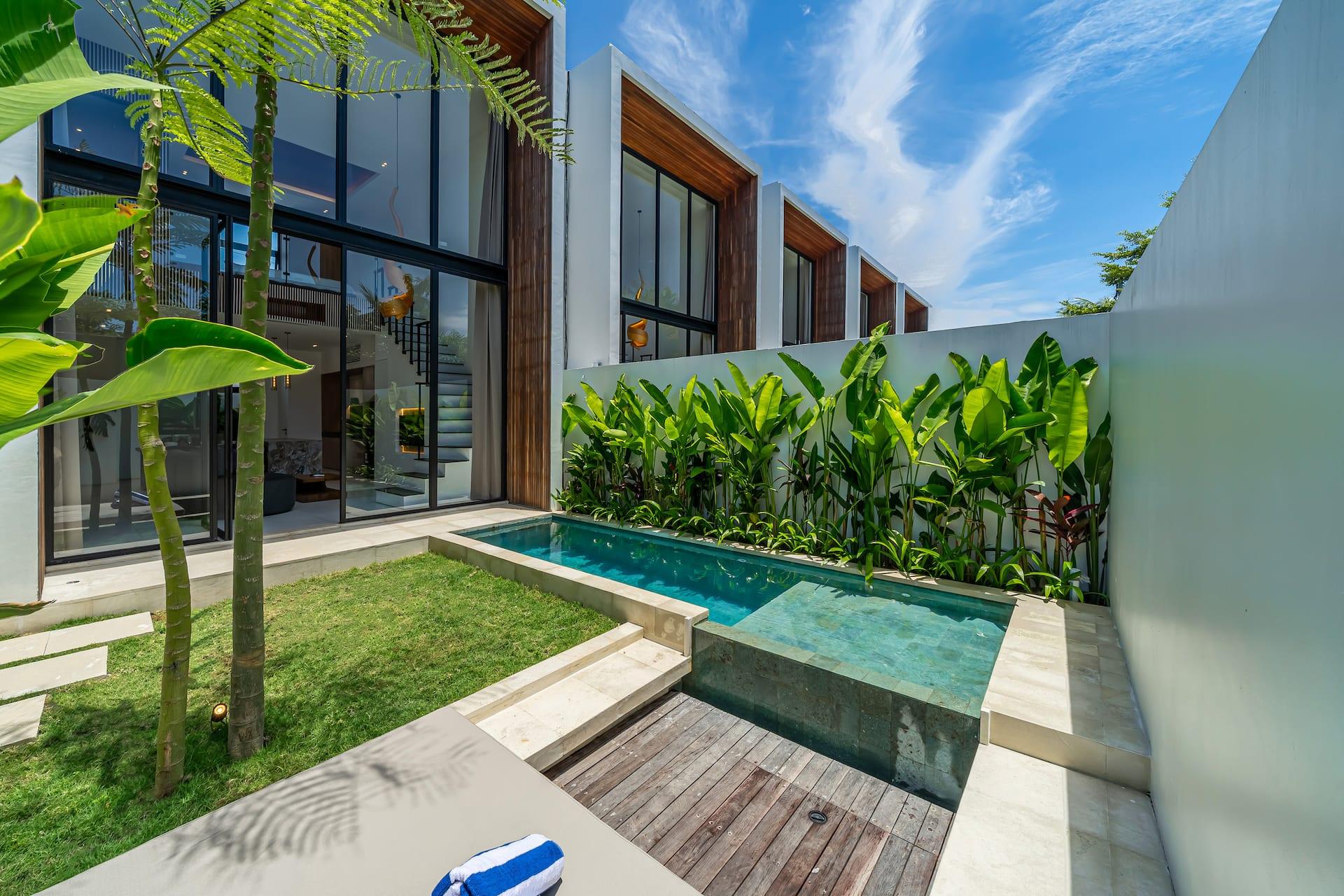 Timber sun deck and pool set against the boundary wall, with heliconia and banana planting behind