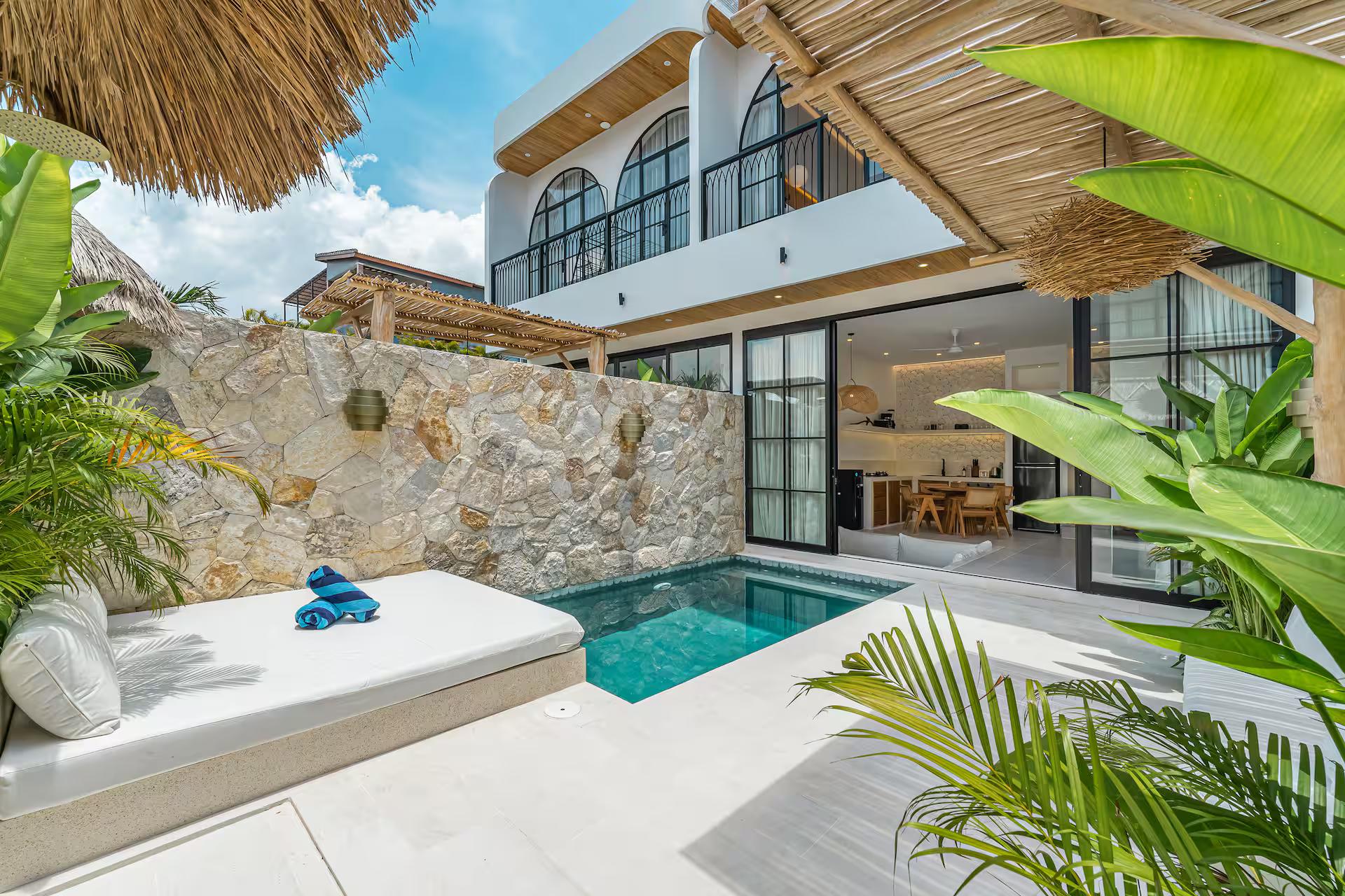 Built-in daybed at the water's edge under a fringe of alang-alang thatch