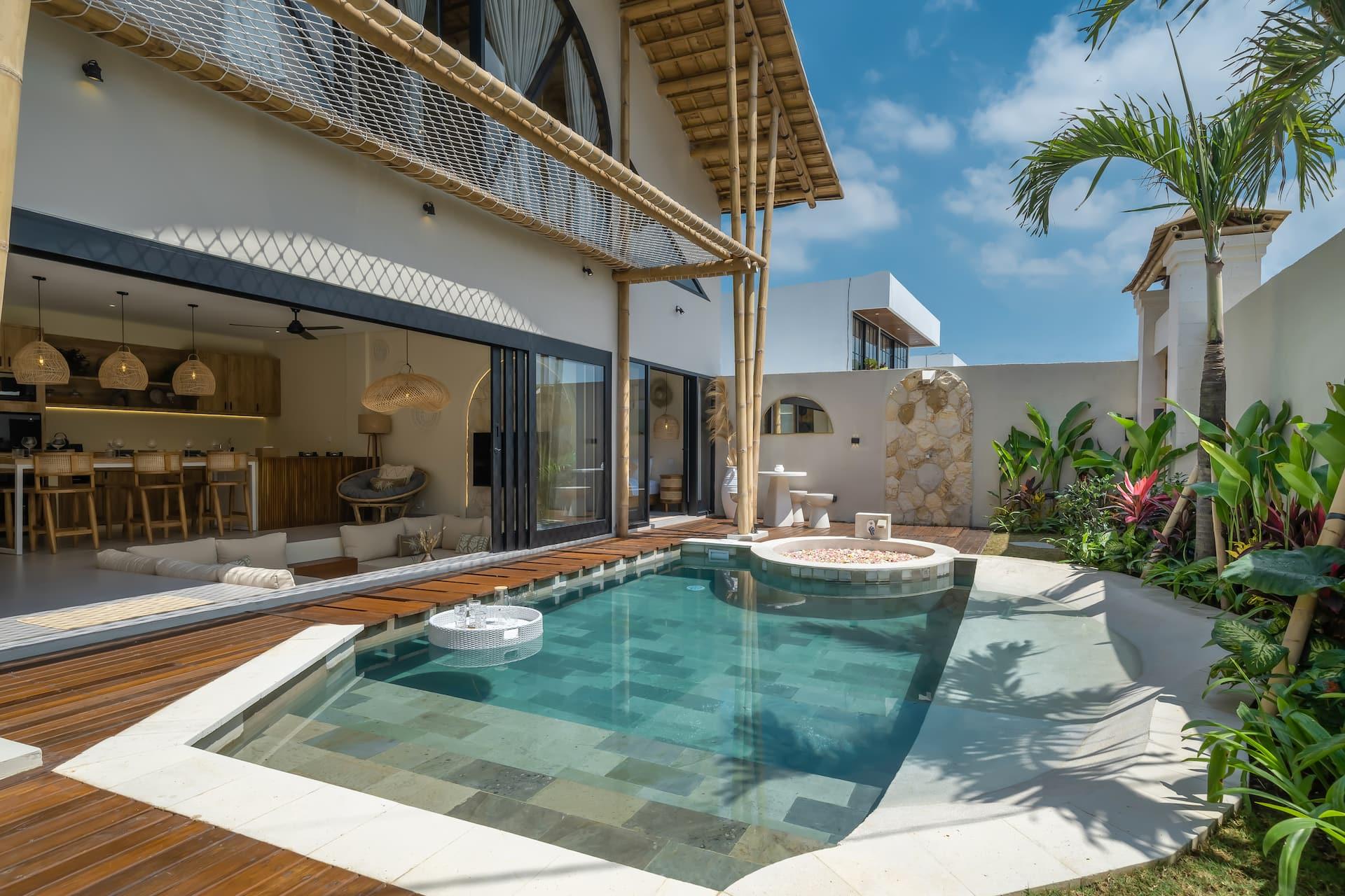 L-shaped pool in green check tile running past the open living pavilion and timber deck