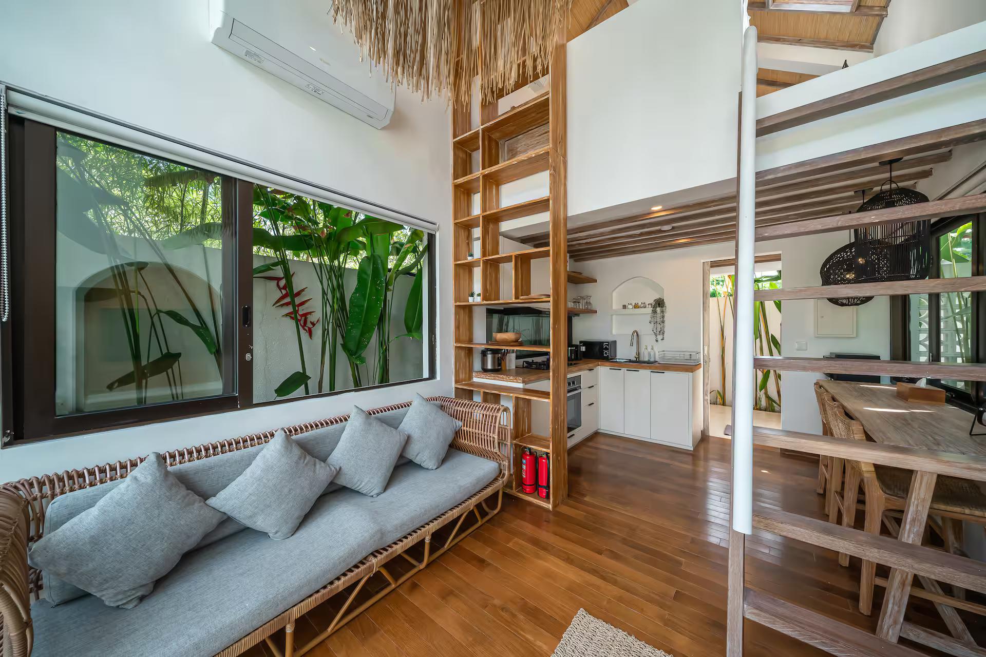 Ground-floor living room with a long banquette, timber shelving and the kitchen beyond