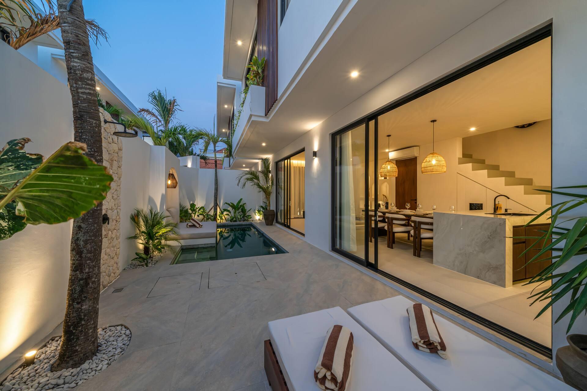Sun loungers on the pool terrace beside full-height sliding glass into the kitchen and dining room