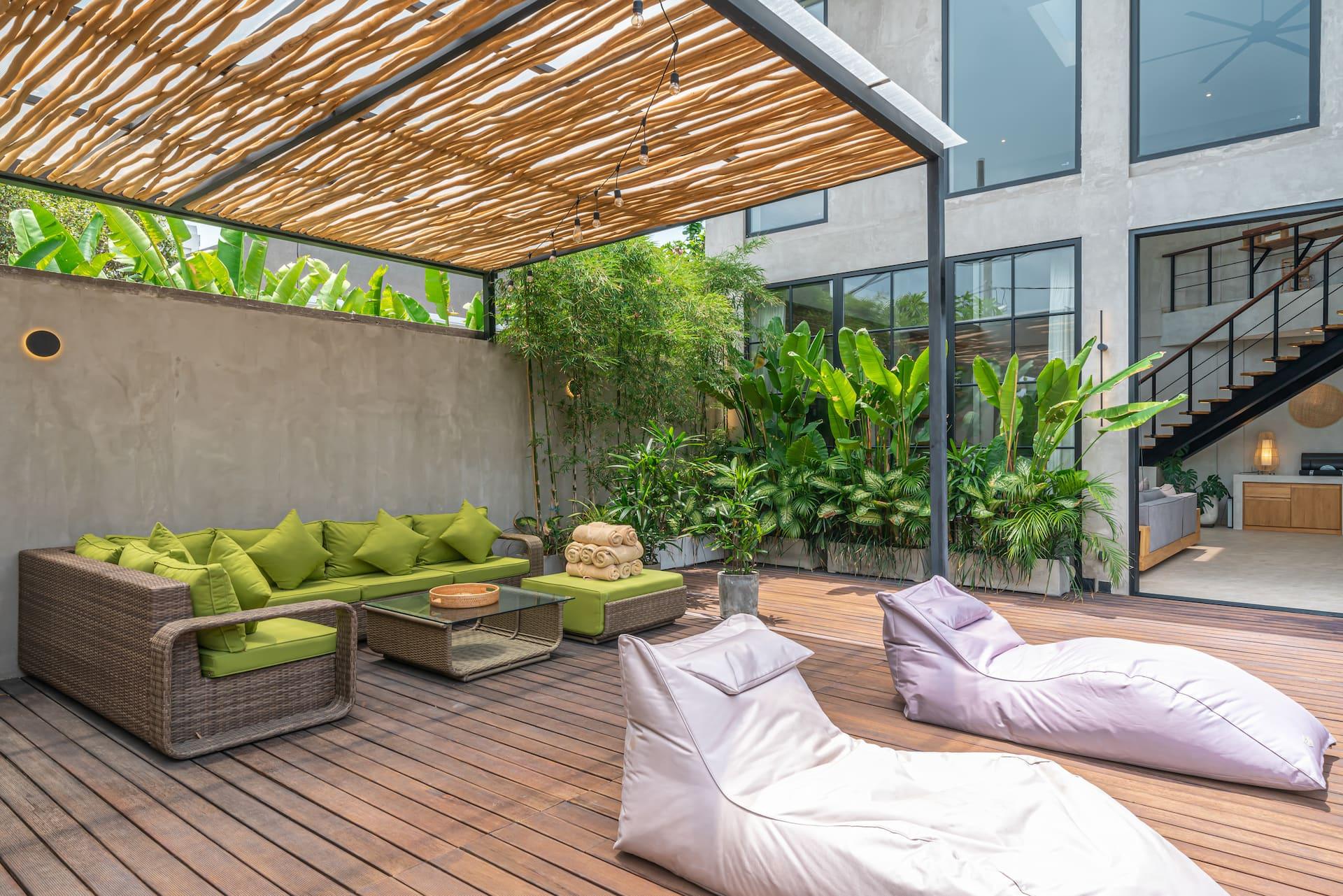 Reed-roofed pergola lounge with rattan sofas and bean-bag loungers on the pool deck