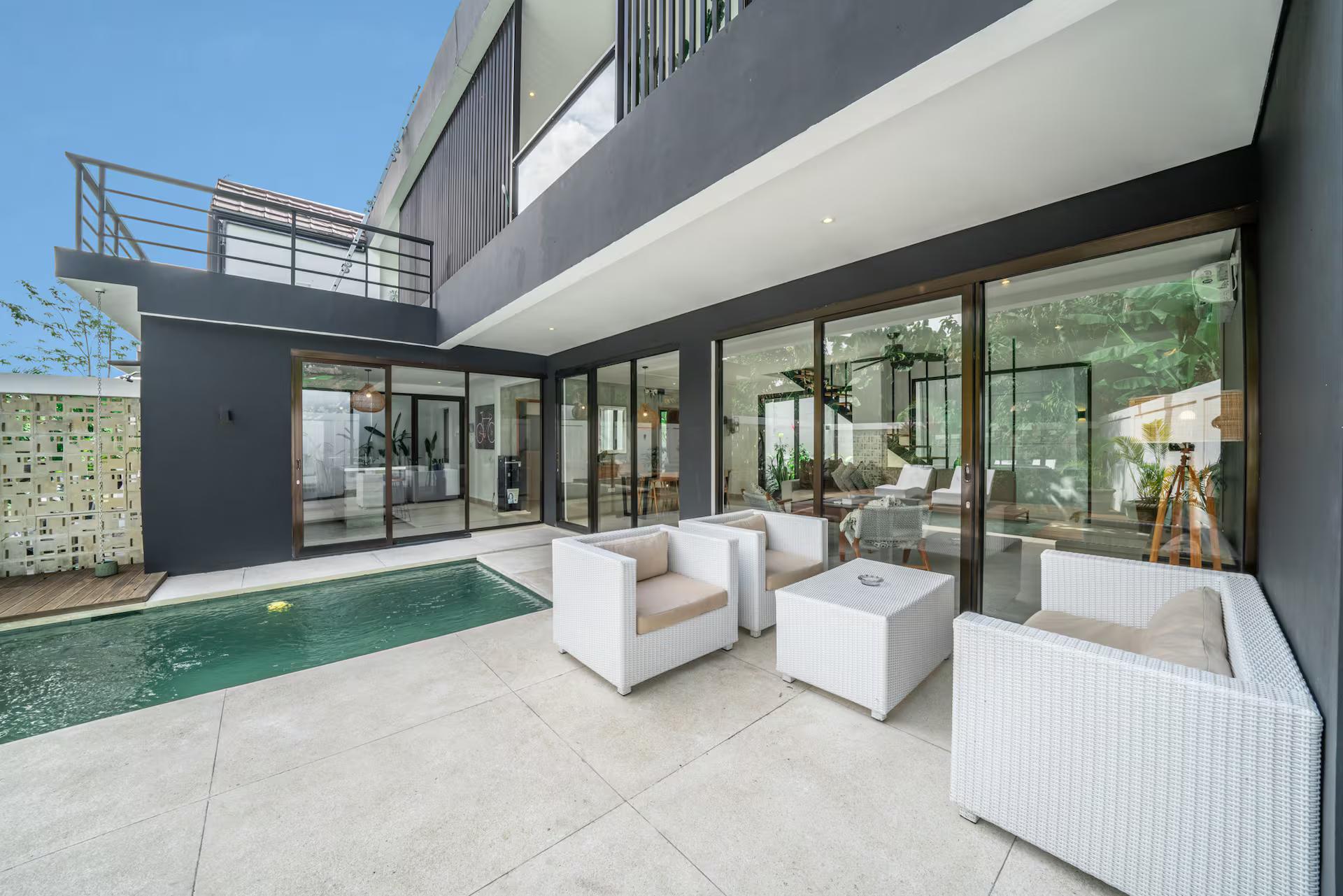 White armchairs and cube tables on the paved terrace at the water's edge