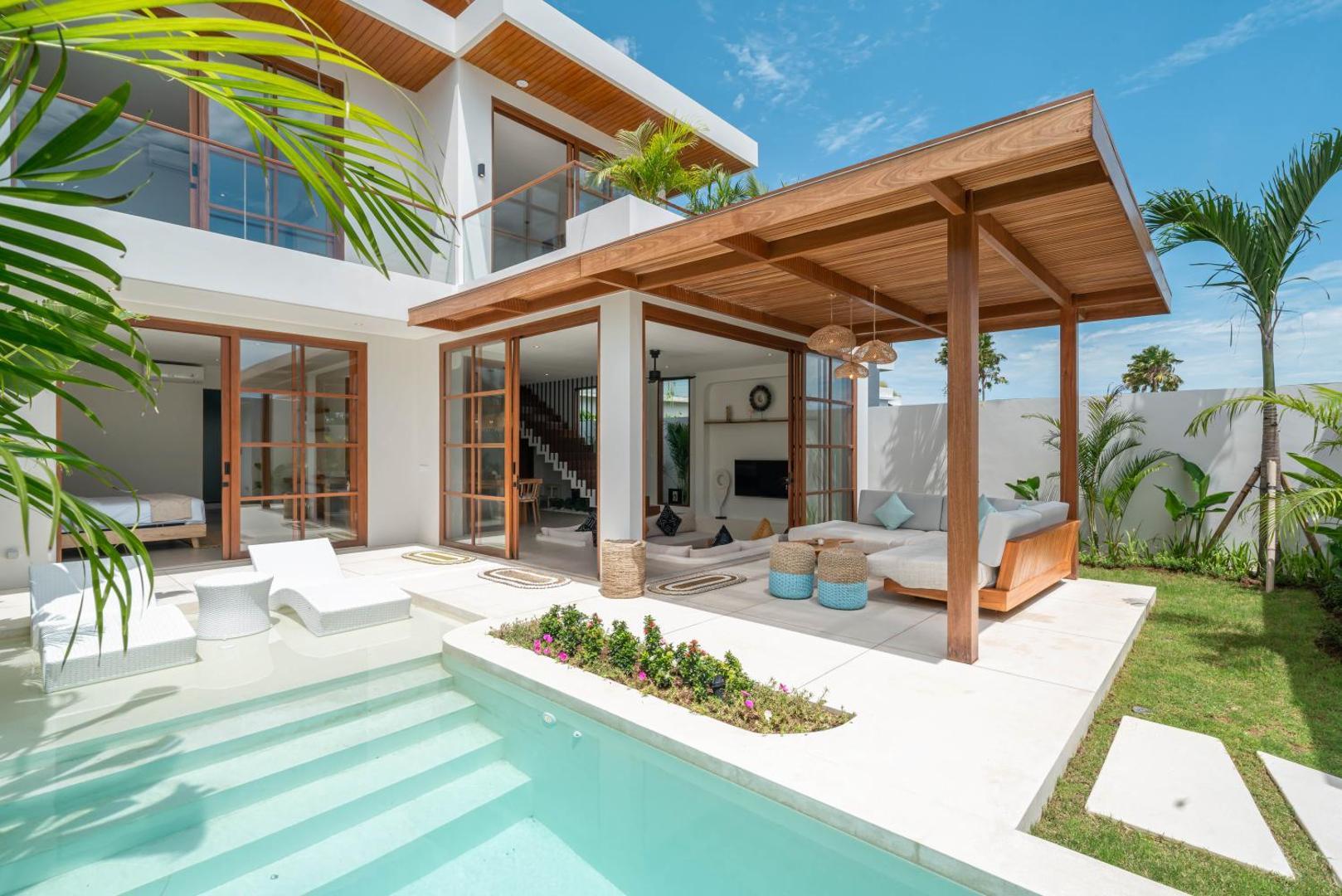 Poolside living pavilion at Villa LouLou with a timber roof, deep grey sofa and the pool a step away