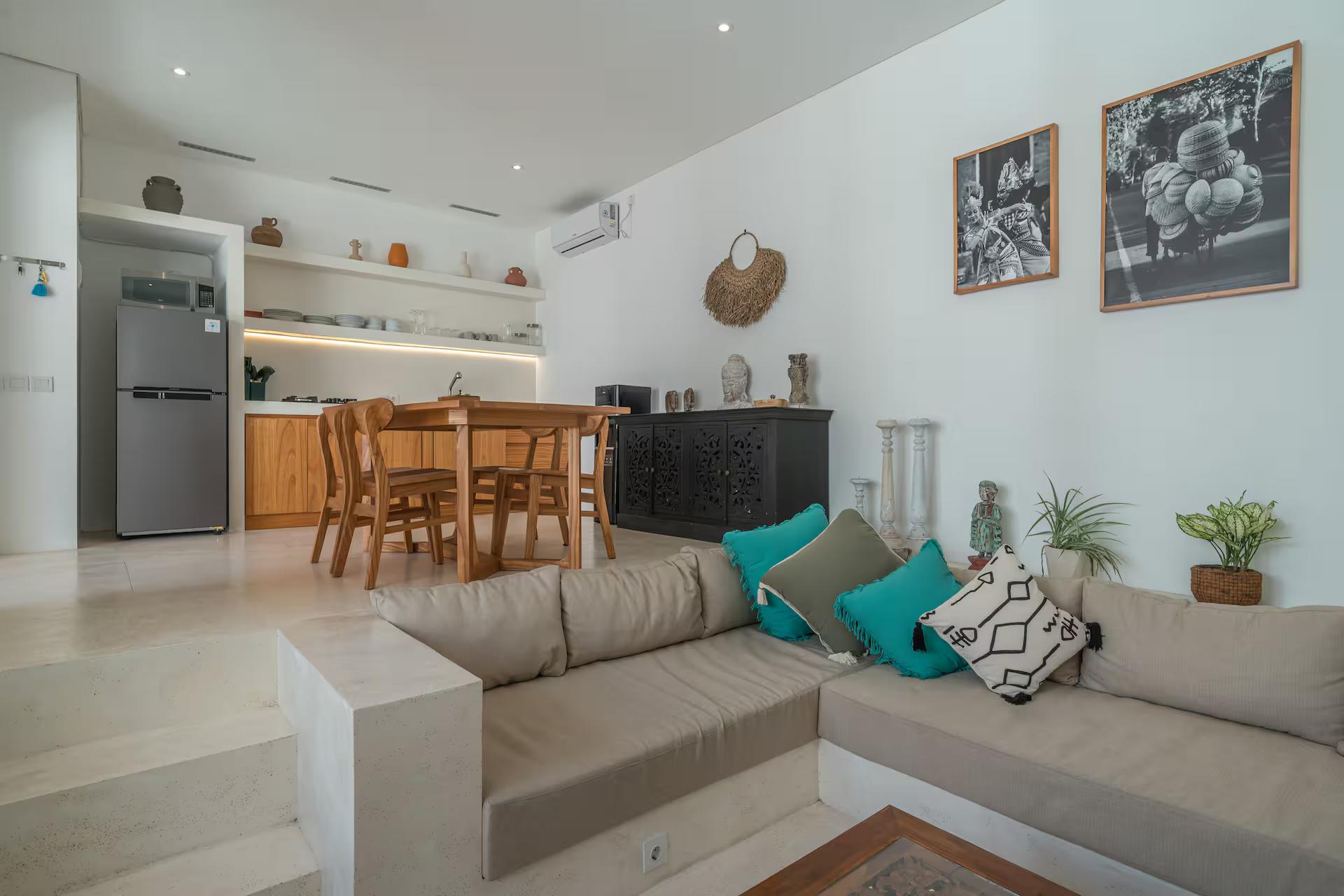 Built-in plaster sofa with linen and turquoise cushions, kitchen and dining behind