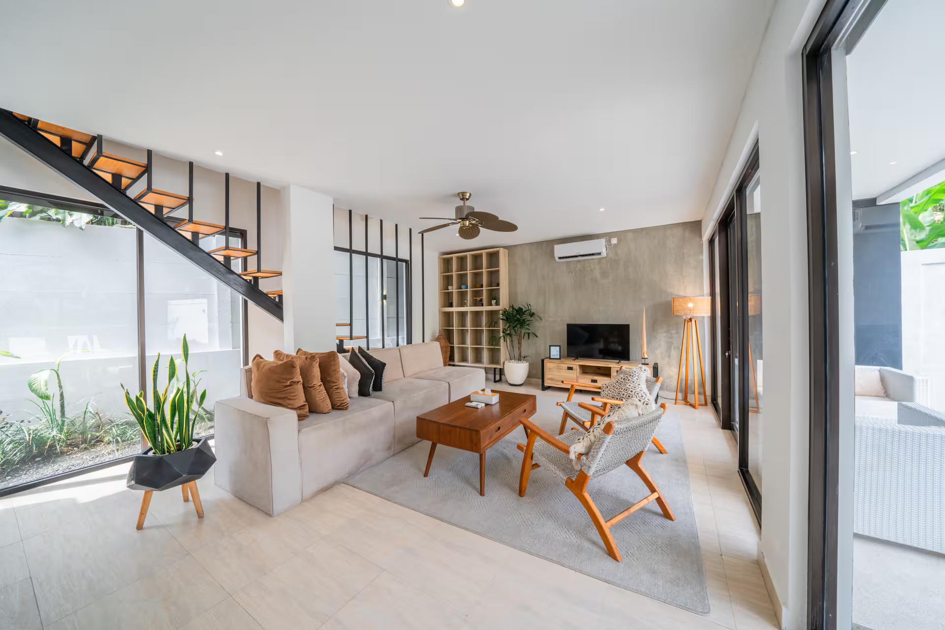 Living room at Villa Anna with cream sofas, woven-back chairs and a floating timber stair