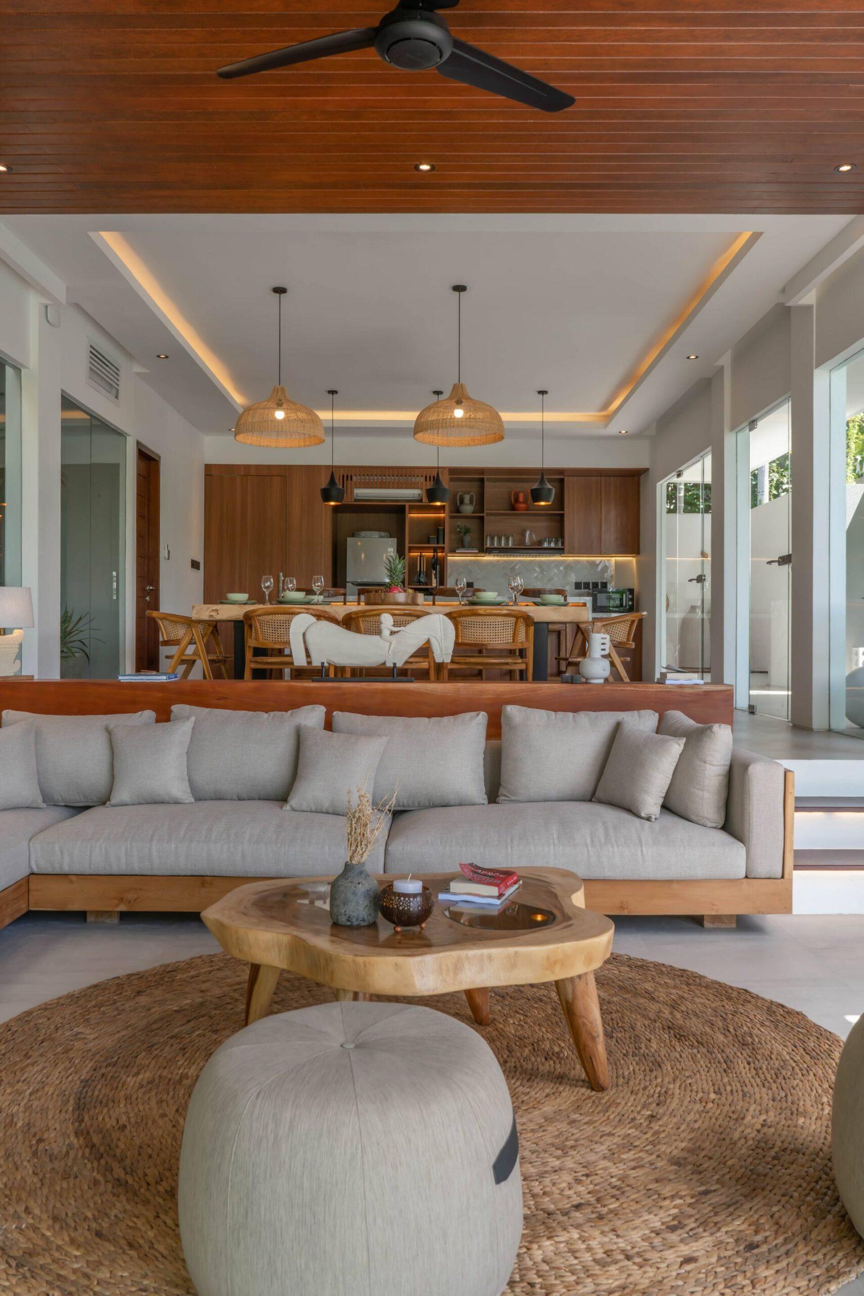 Deep linen sofa on a round jute rug at Villa Luna, the kitchen island beyond