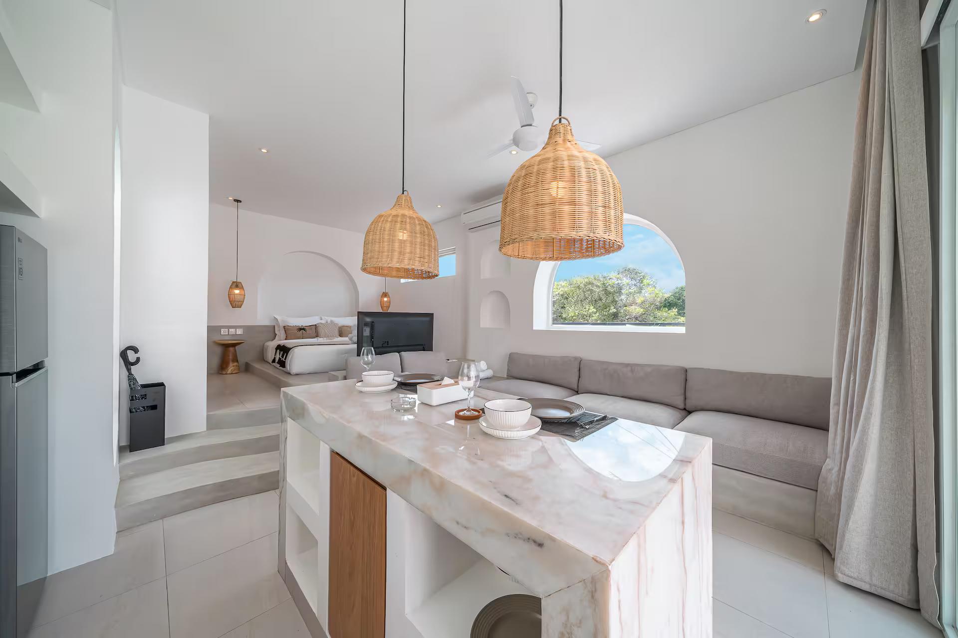 Open-plan room at Las Casas 17 with a marble island and a long built-in banquette sofa