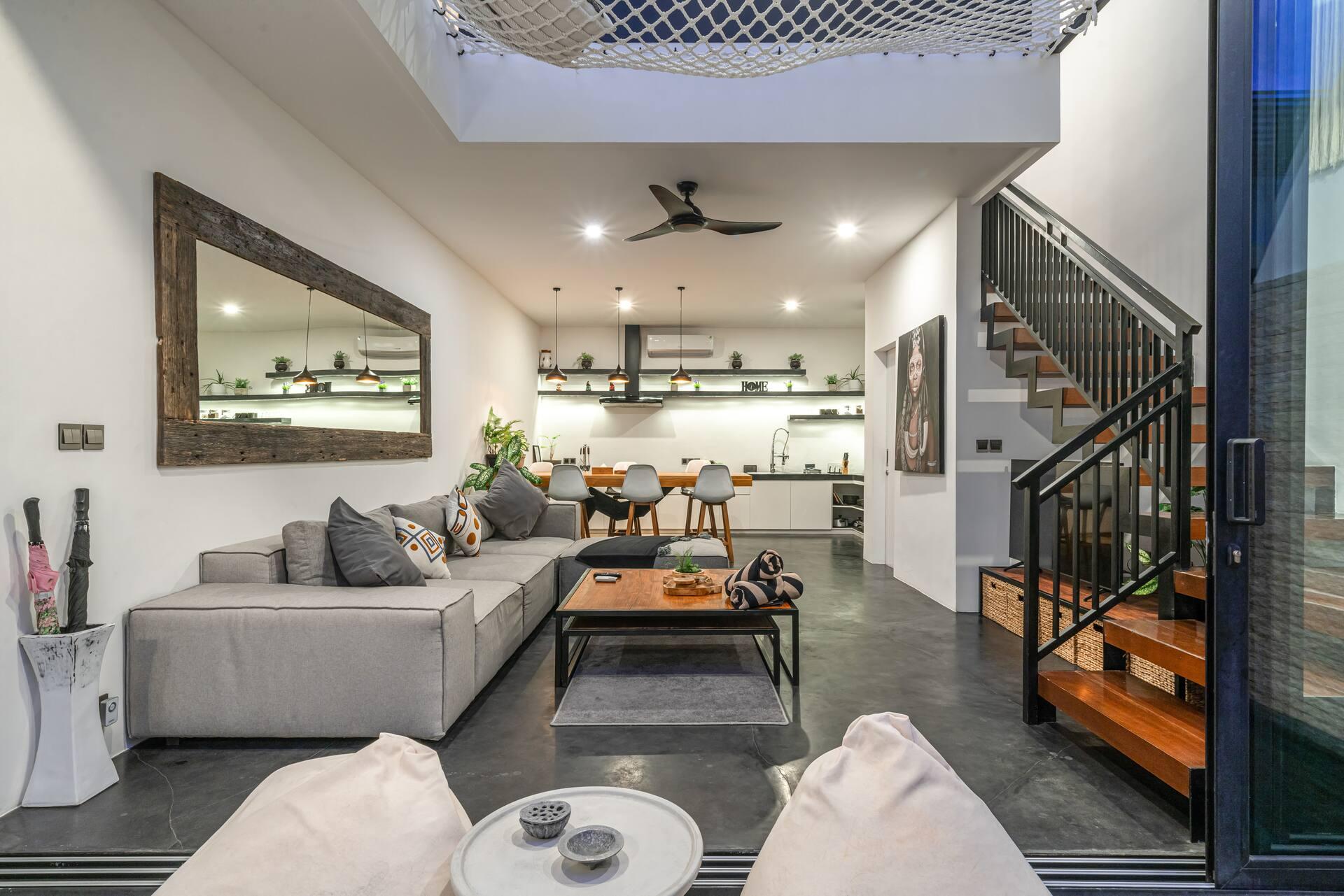 Living room in polished concrete with a grey sectional and an oversized framed mirror