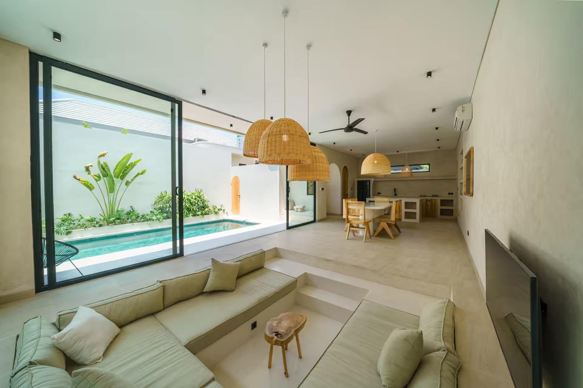 Sunken lounge in stone-coloured linen under rattan pendants, open to the planted courtyard