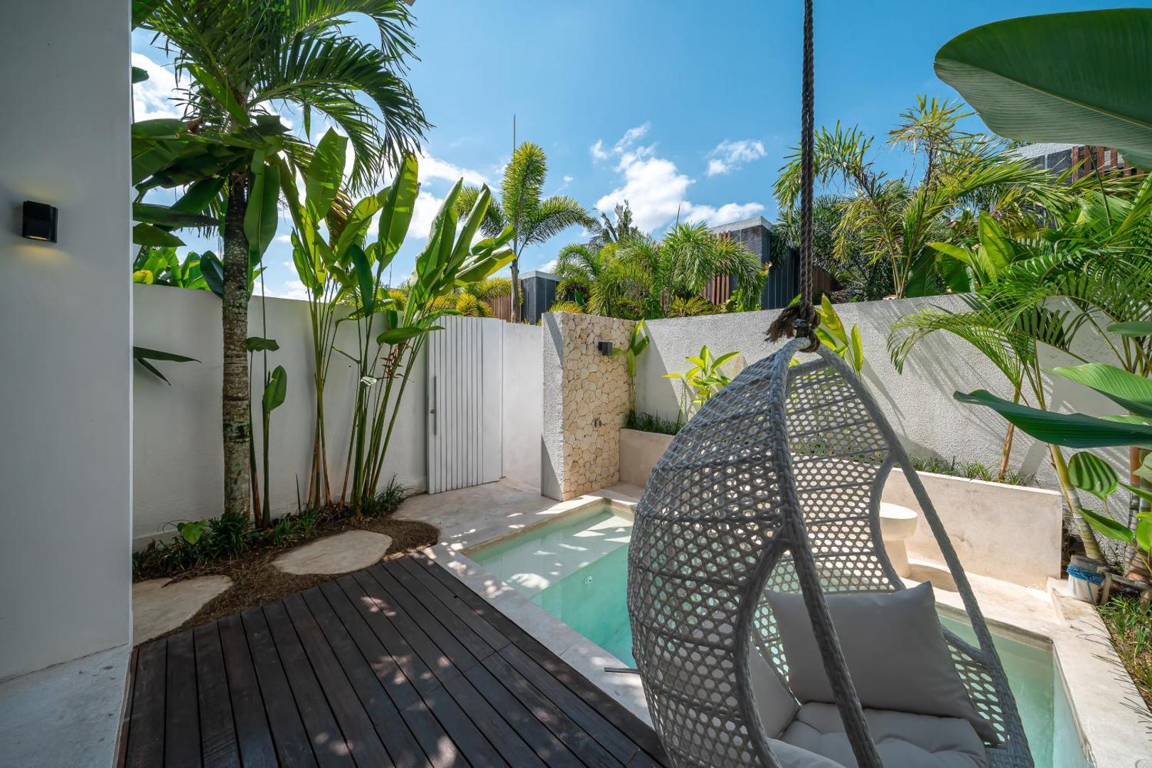 Hardwood deck along the plunge pool, egg chair swinging under banana palms