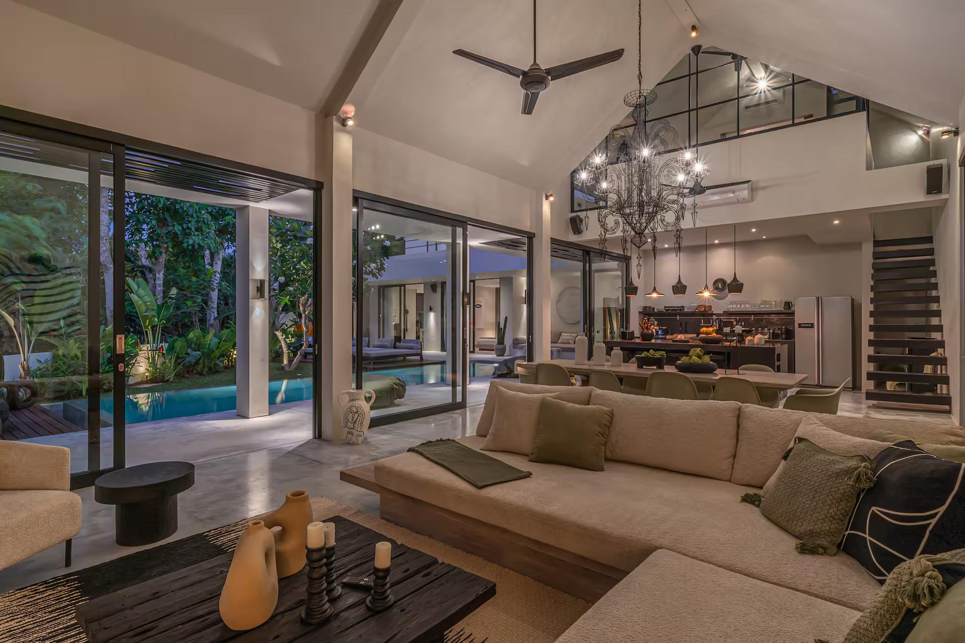 Open living room at Villa Prana with a deep sectional sofa facing the pool through glass