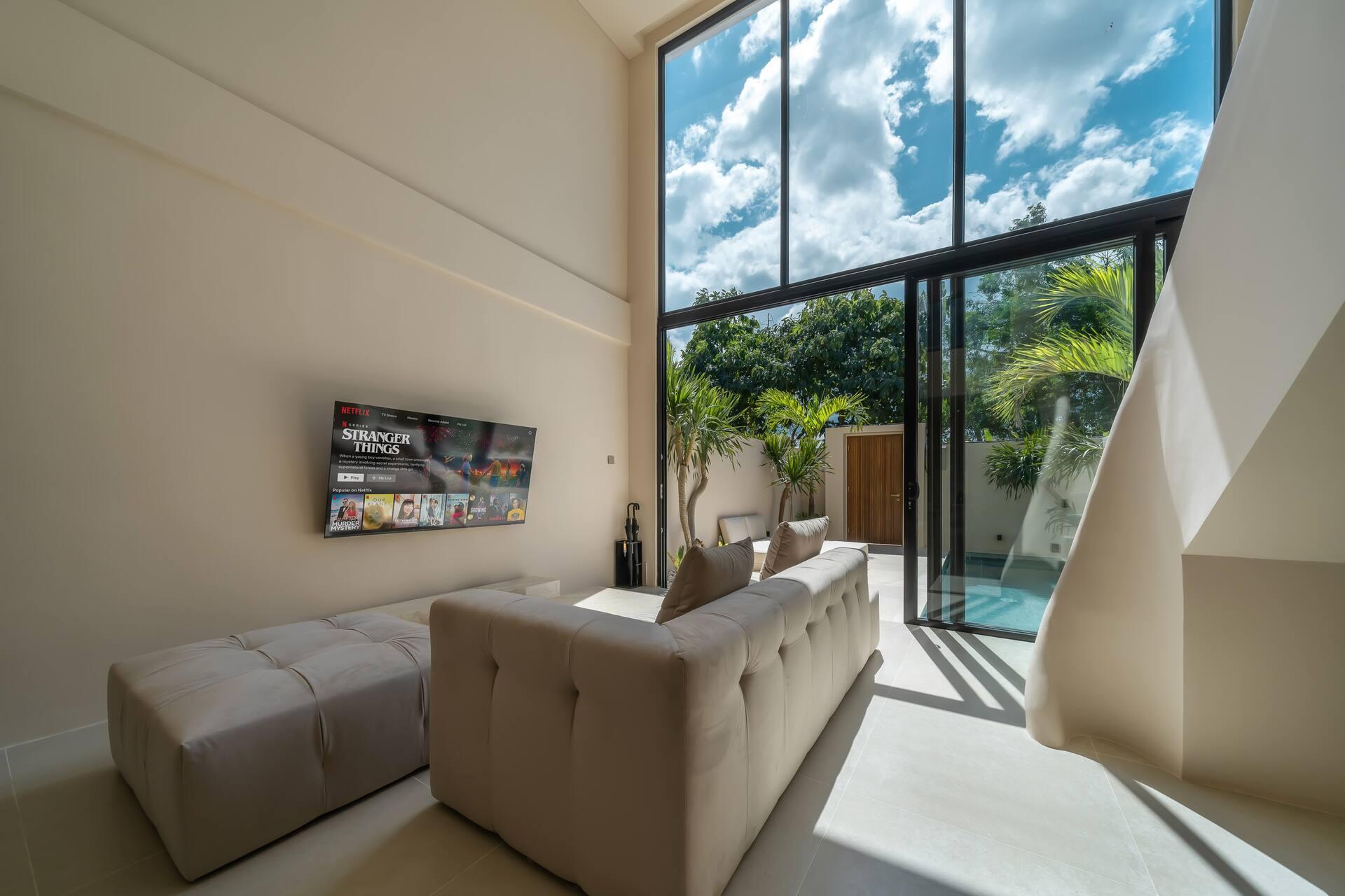 Double-height living room at Enso 4 with a tufted sofa and a full wall of glazing