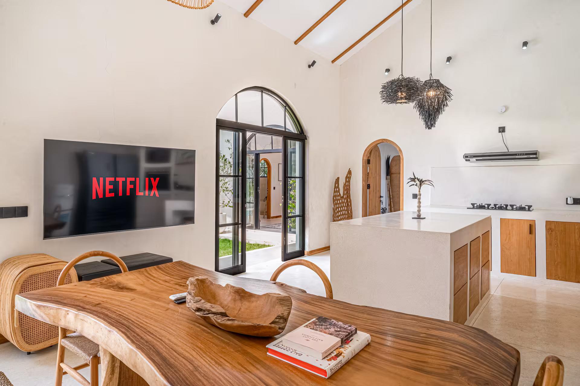 Living room at the macan Bingin under timber rafters, live-edge table and open kitchen