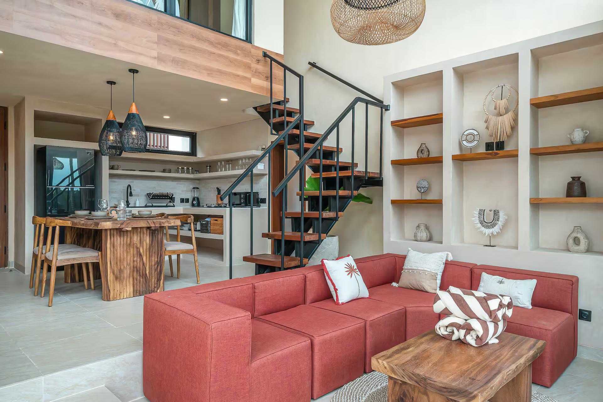 Coral modular sectional below plastered display niches, with the steel stair climbing to the mezzanine