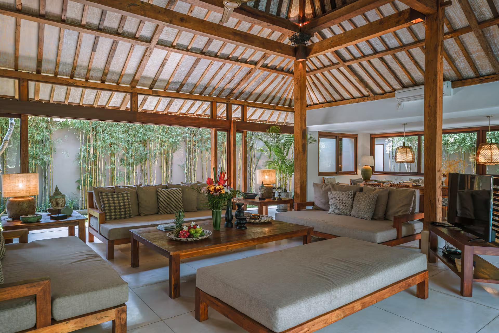 Open living pavilion at Villa Amore, daybed sofas beneath an exposed timber truss ceiling