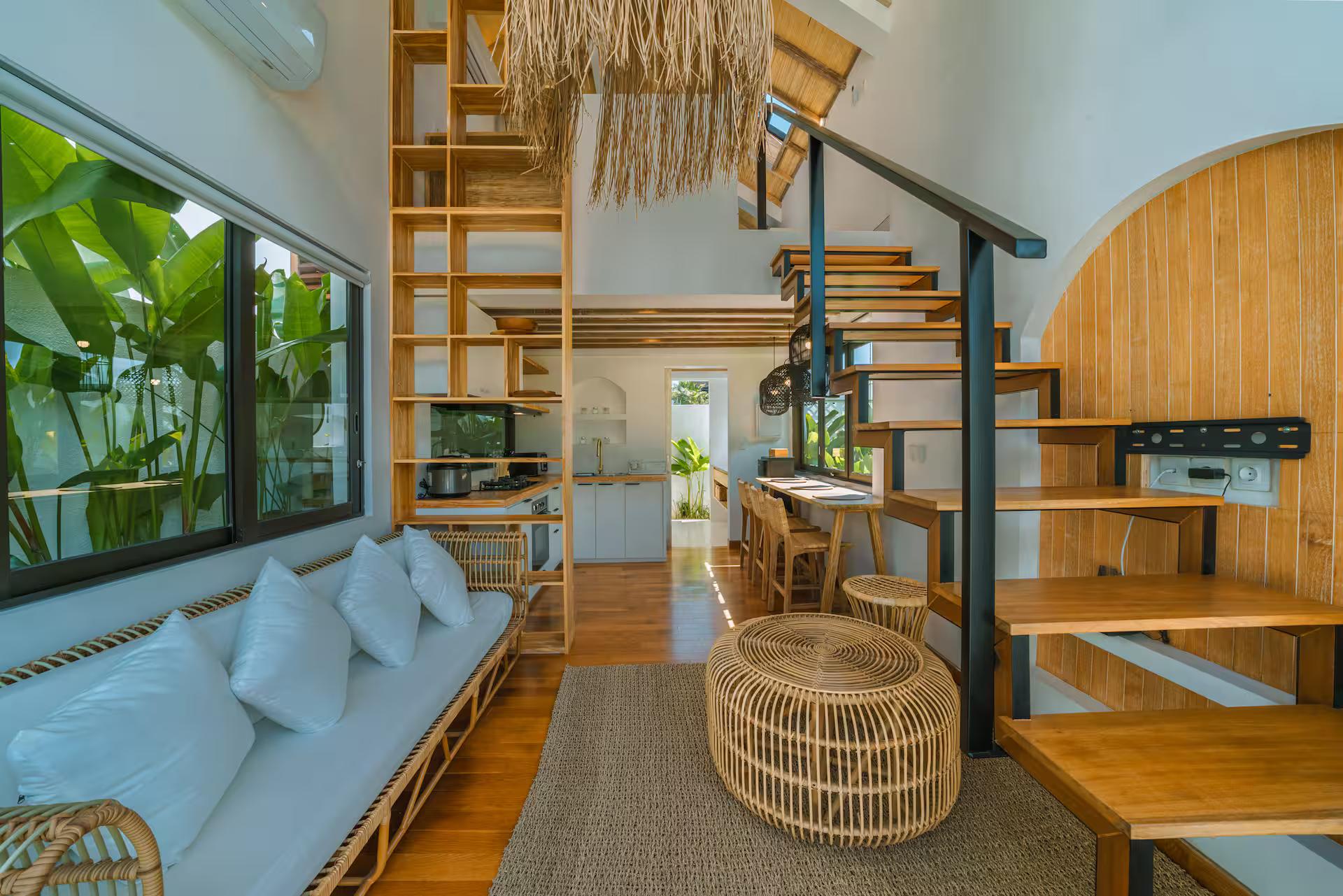 Living space at Villa Tiny with a built-in banquette, jute rug and open timber stair