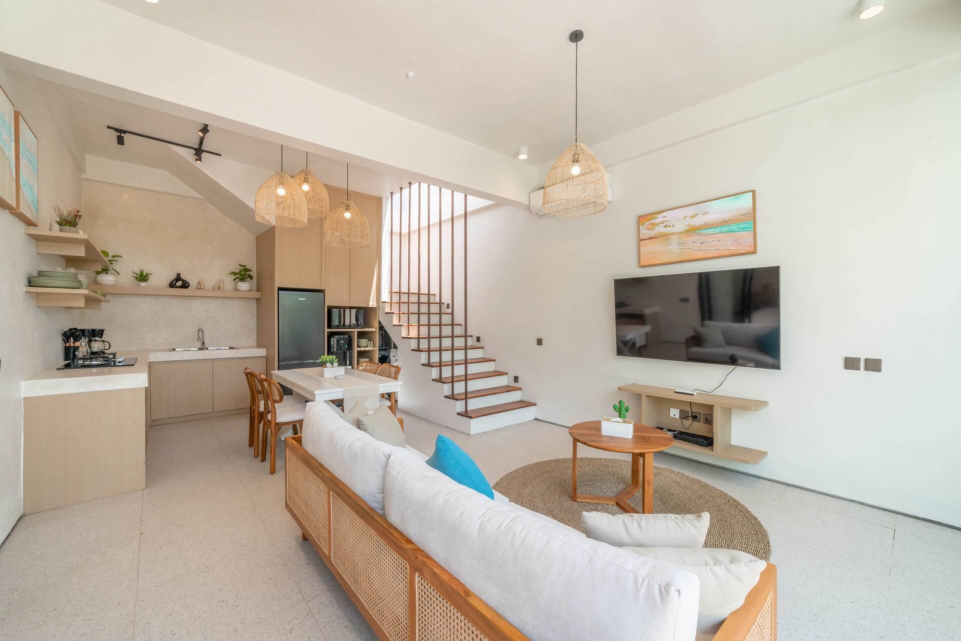 Open-plan living, dining and kitchen at Casa Sirena, under rattan pendants and a raised white ceiling
