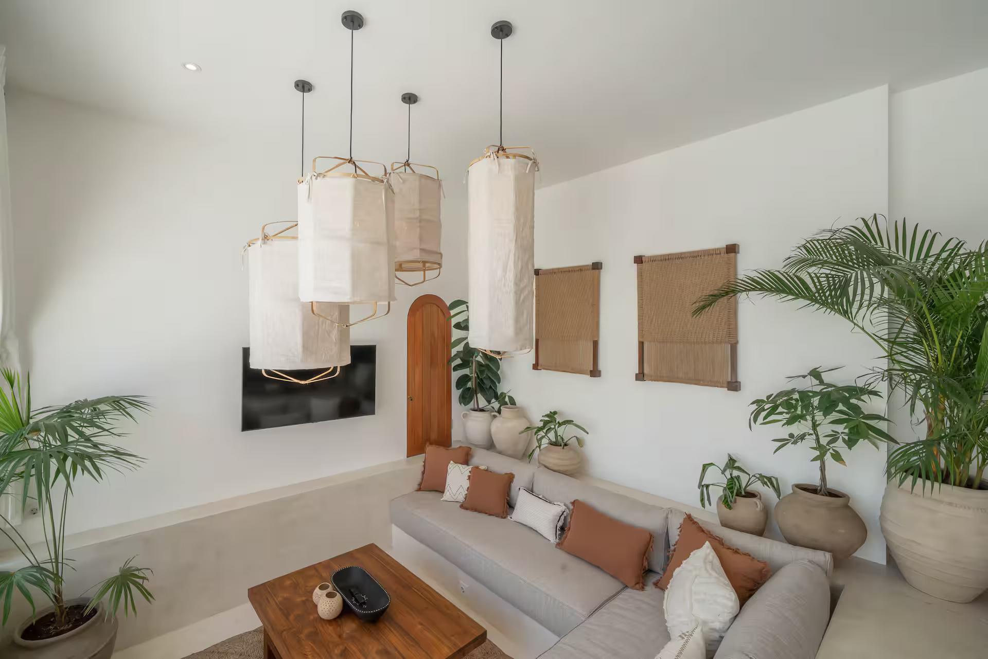 Living room at Villa Heiwa, a long low sectional beneath tall paper-and-rattan pendants