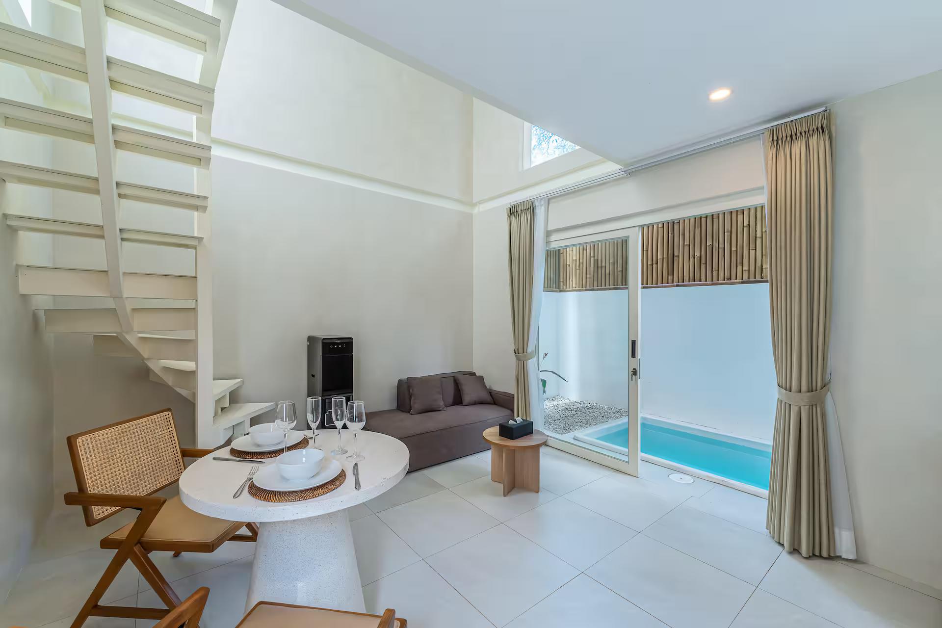 Living room with a terrazzo dining table, caned chairs and the white stair rising behind