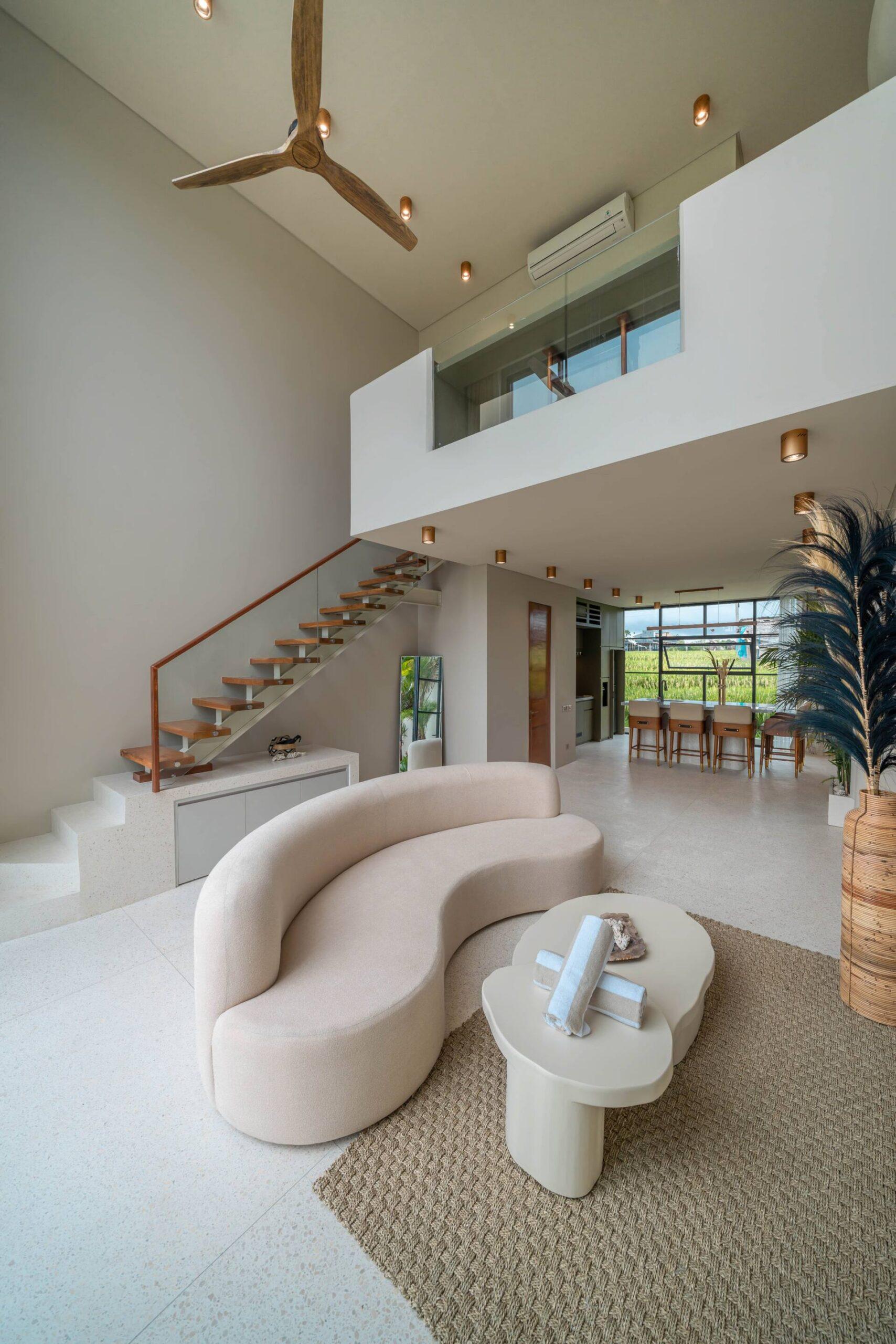 Double-height living room with a curved boucle sofa and a floating timber staircase