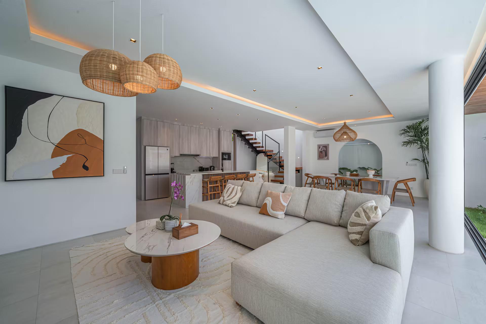 Double-height living room at Villa Jenna with a cream sectional and floating timber staircase