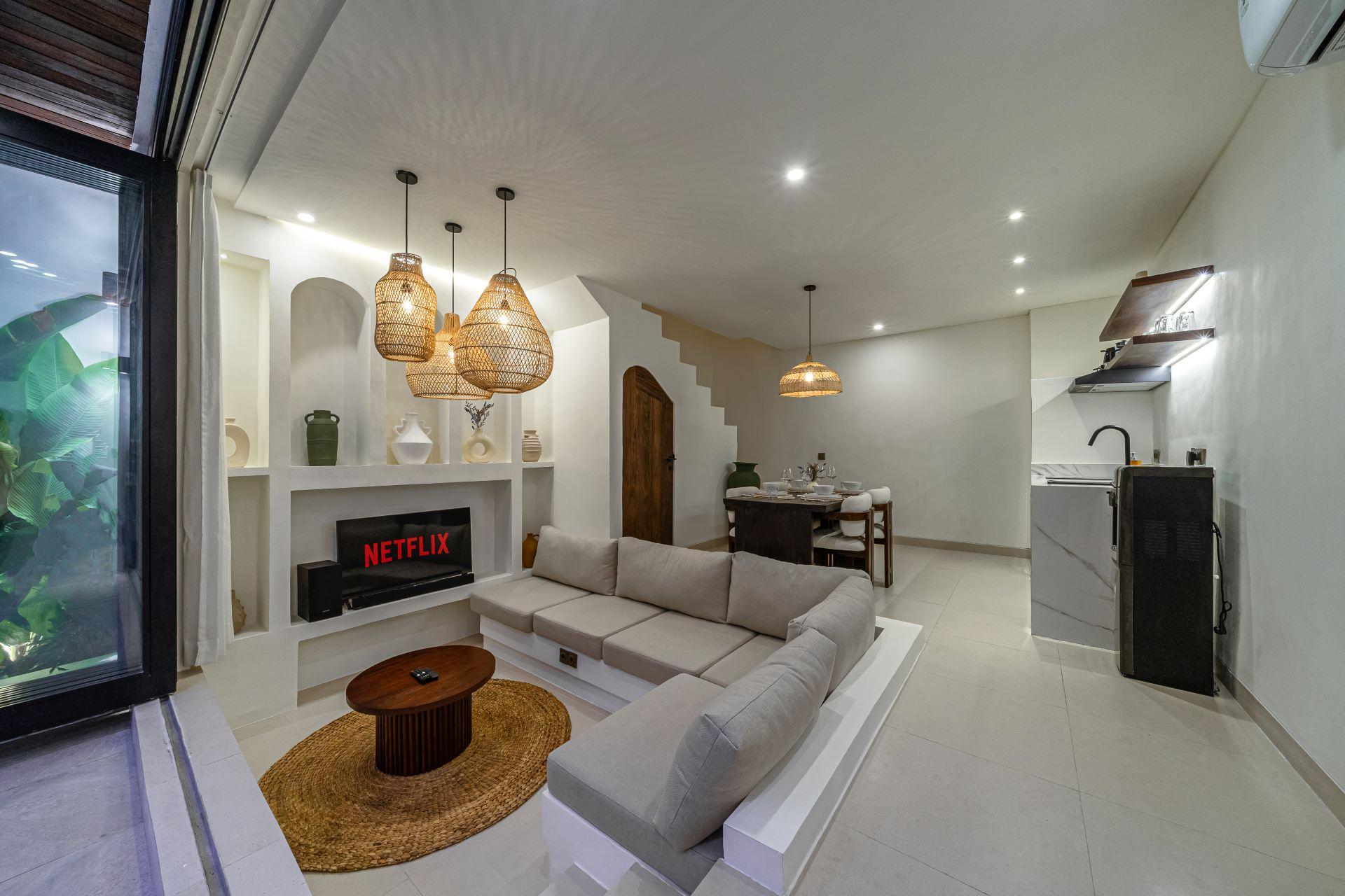 Living room with rattan pendants and a television recessed into a white plaster niche wall