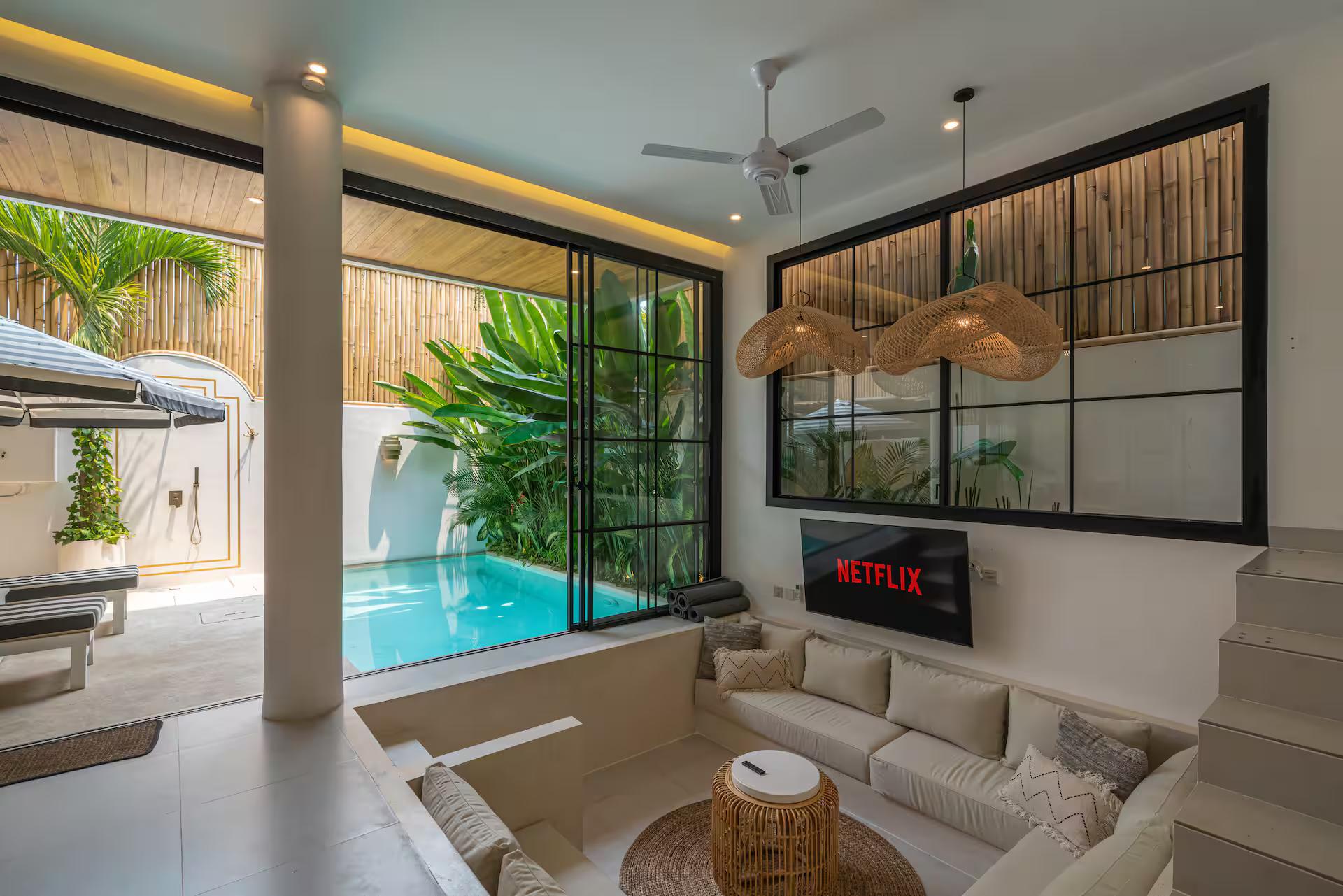 Sunken lounge at Villa Sagu opening through a glass wall onto the pool deck